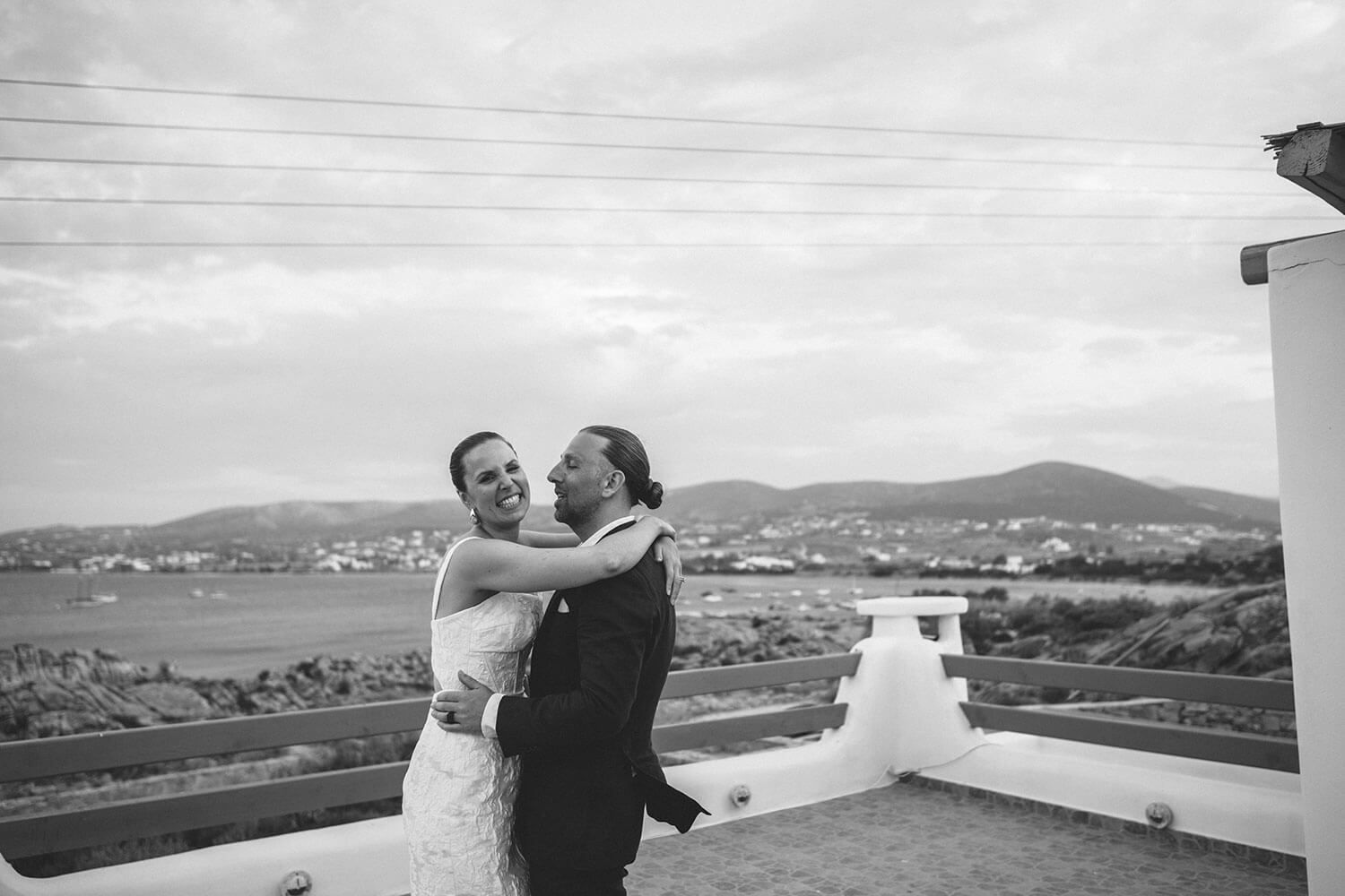Newlyweds dancing on the rooftop with the Aegean sea behind them