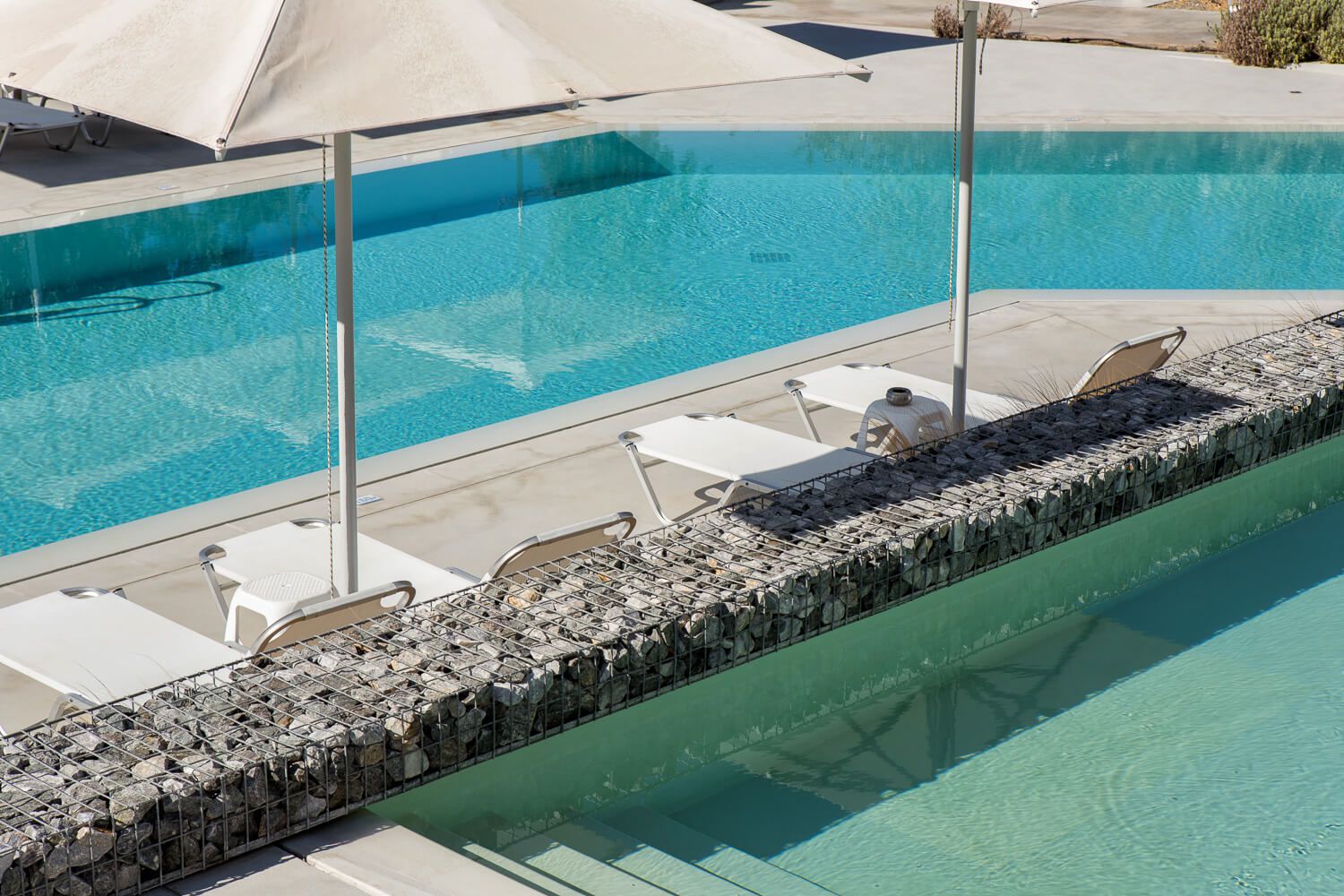 Minimalist sun loungers surrounding a luxury hotel pool in Ios