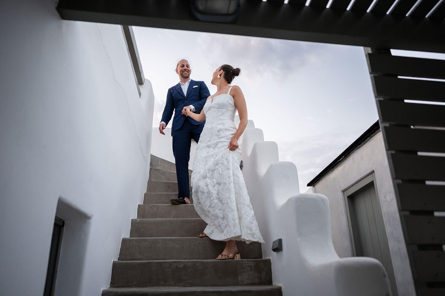 Newlyweds walking together on the rooftop with the Aegean sea behind them