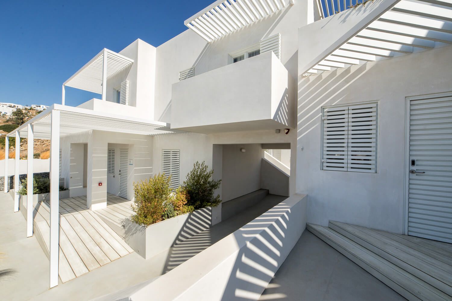 Mediterranean hotel exterior with pergola, shuttered windows, and minimalist architecture in Ios.