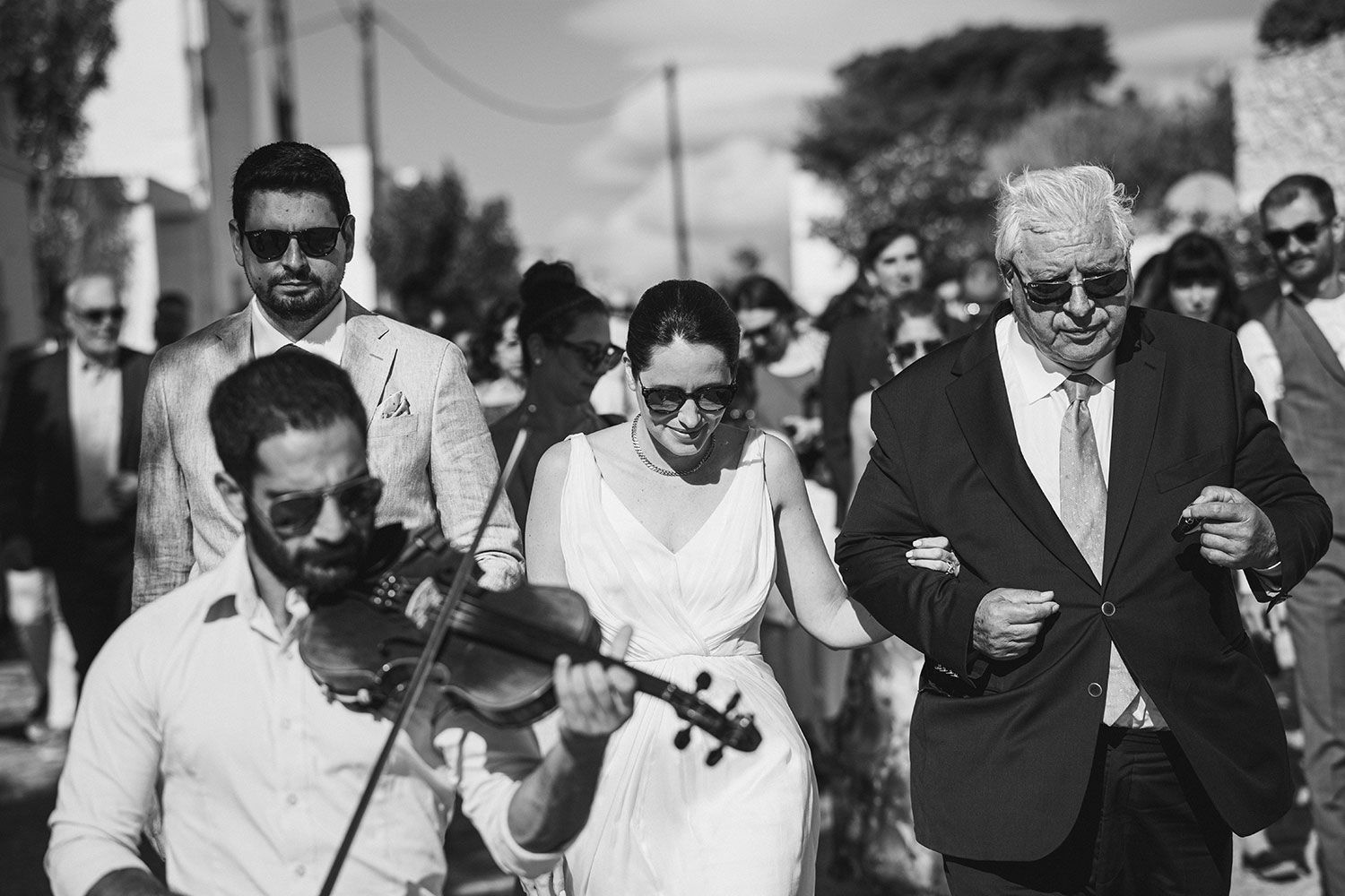 The bride is heading to the church acompanied by local musicians in Aigiali Amorgos