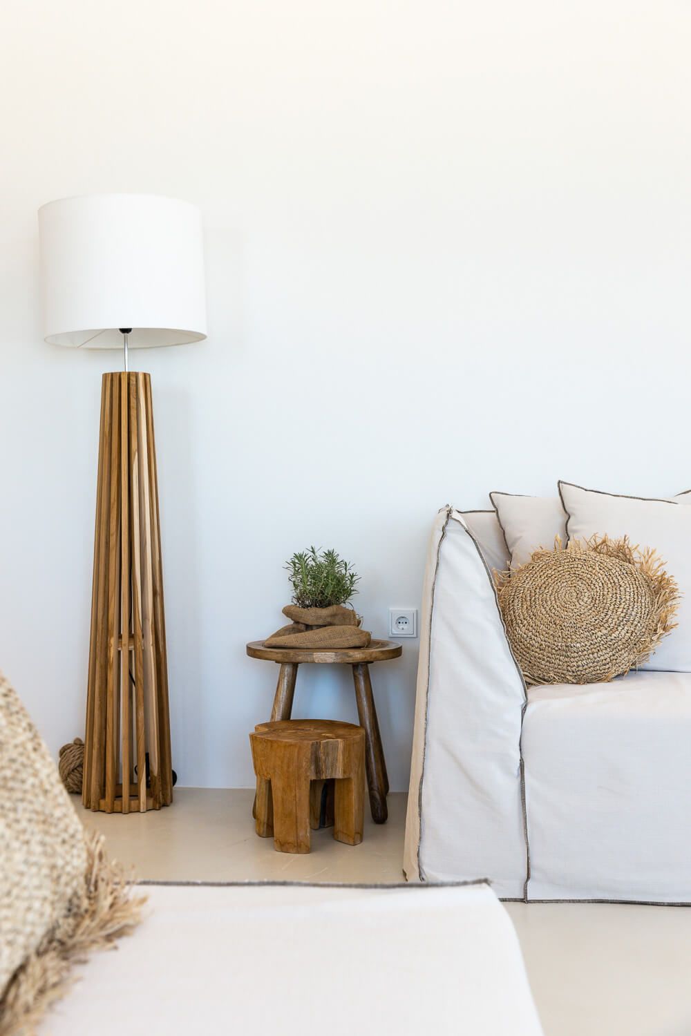 Minimalist coastal living room decor featuring white sofa, woven basket, wooden side table and natural textiles.