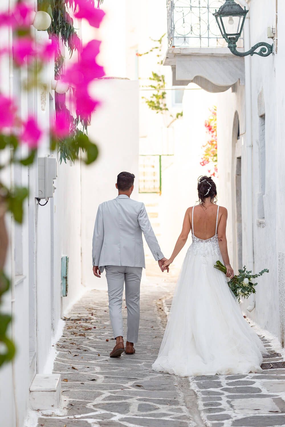 Candid stroll of the newlyweds holding hands in the old town of Parikia
