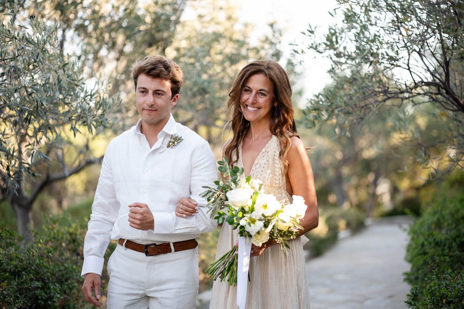 Bride Kathy walking down the aisle escorted by her son  for her small Paros wedding