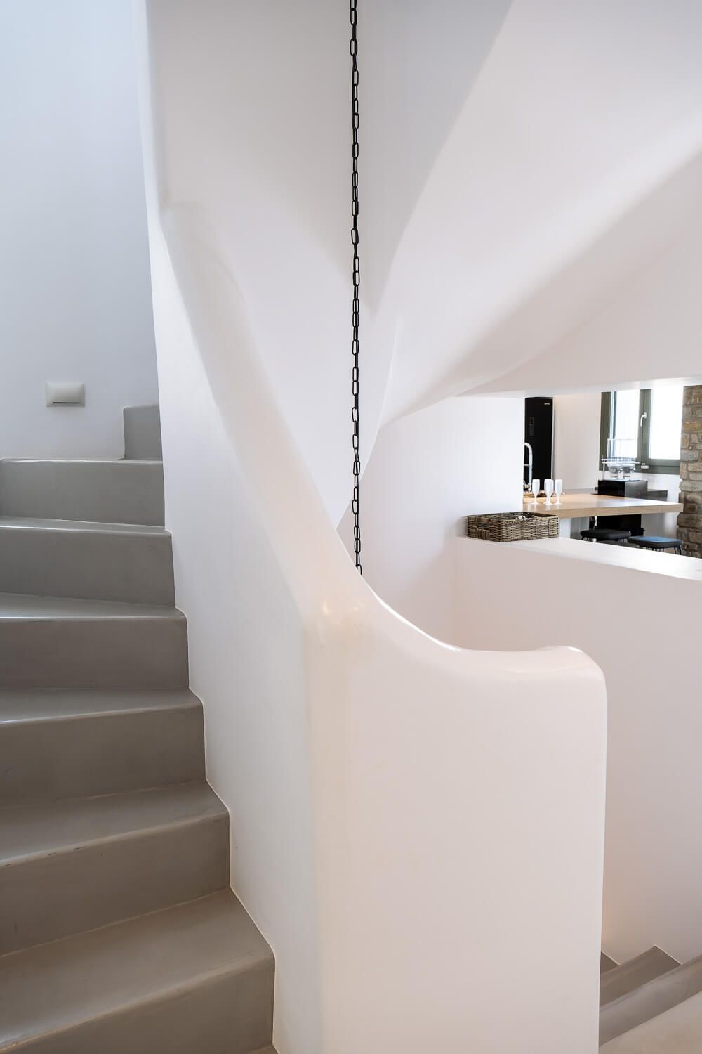 Modern minimalist white curved staircase with smooth walls and clean lines creates an elegant architectural flow.