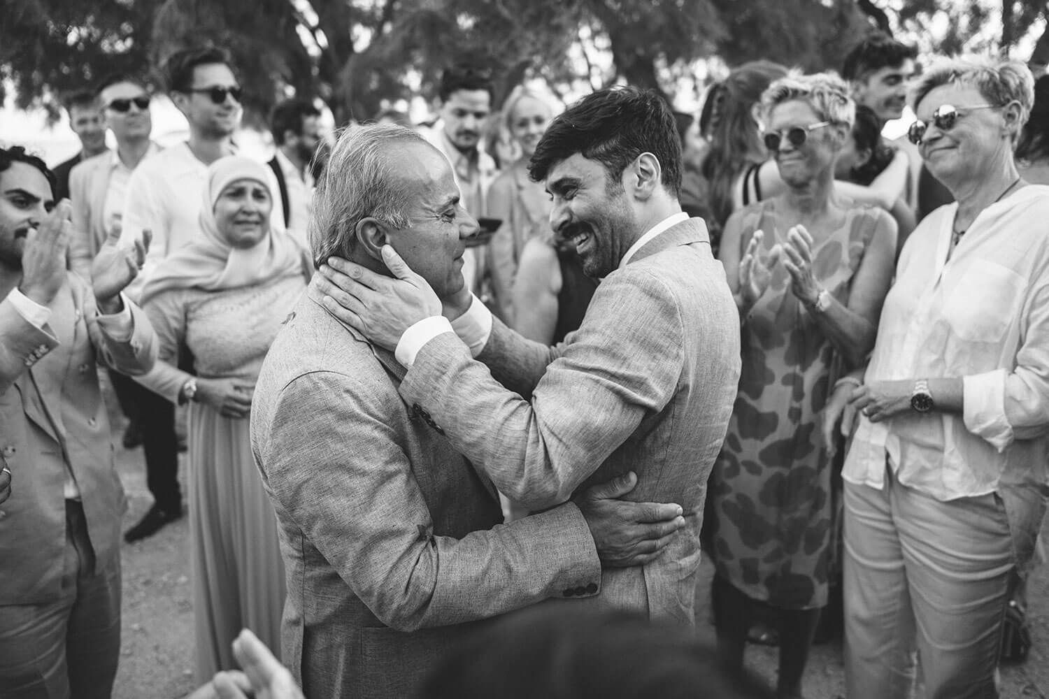 Wedding guests celebrate during a joyful outdoor reception in black and white photography.