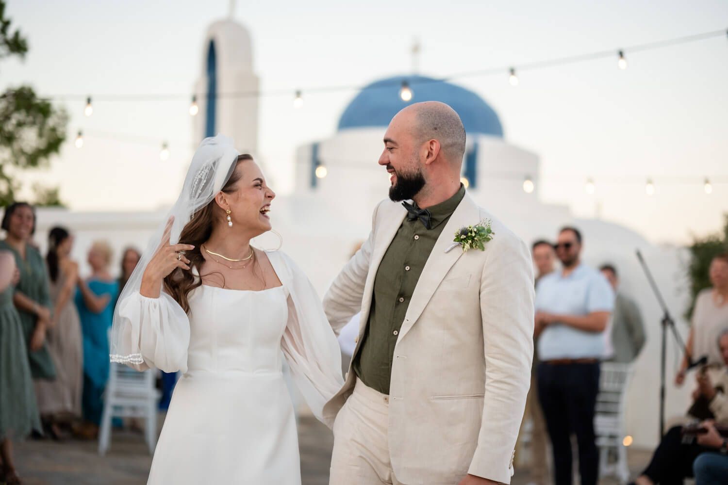 Smiling bride and groom hold hands after outdoor wedding ceremony at Secret View Events Paros.
