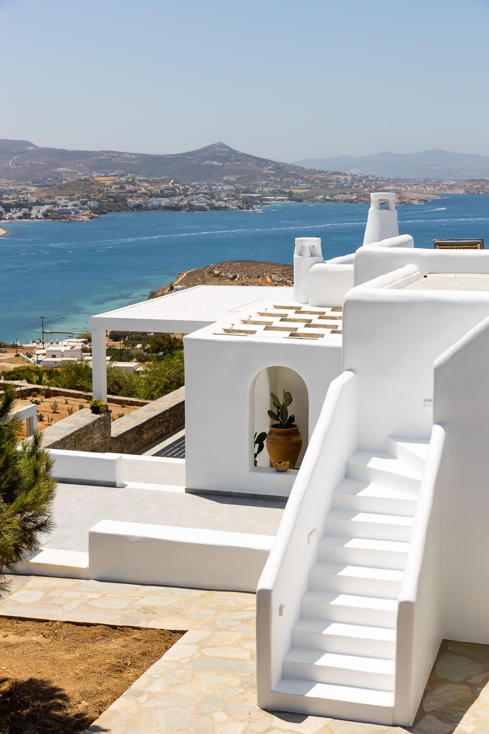 White Cycladic architecture with stairs and sea view in Paros, Greece, under clear blue sky.