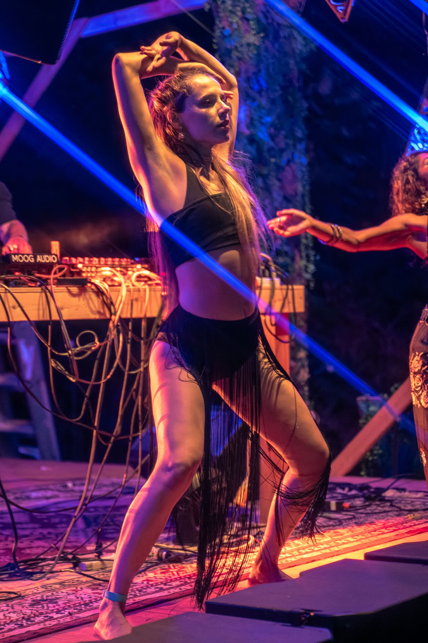 Une femme danse sur la scène de l’Anatha Fest à Montréal, entourée de lumières éclatantes.