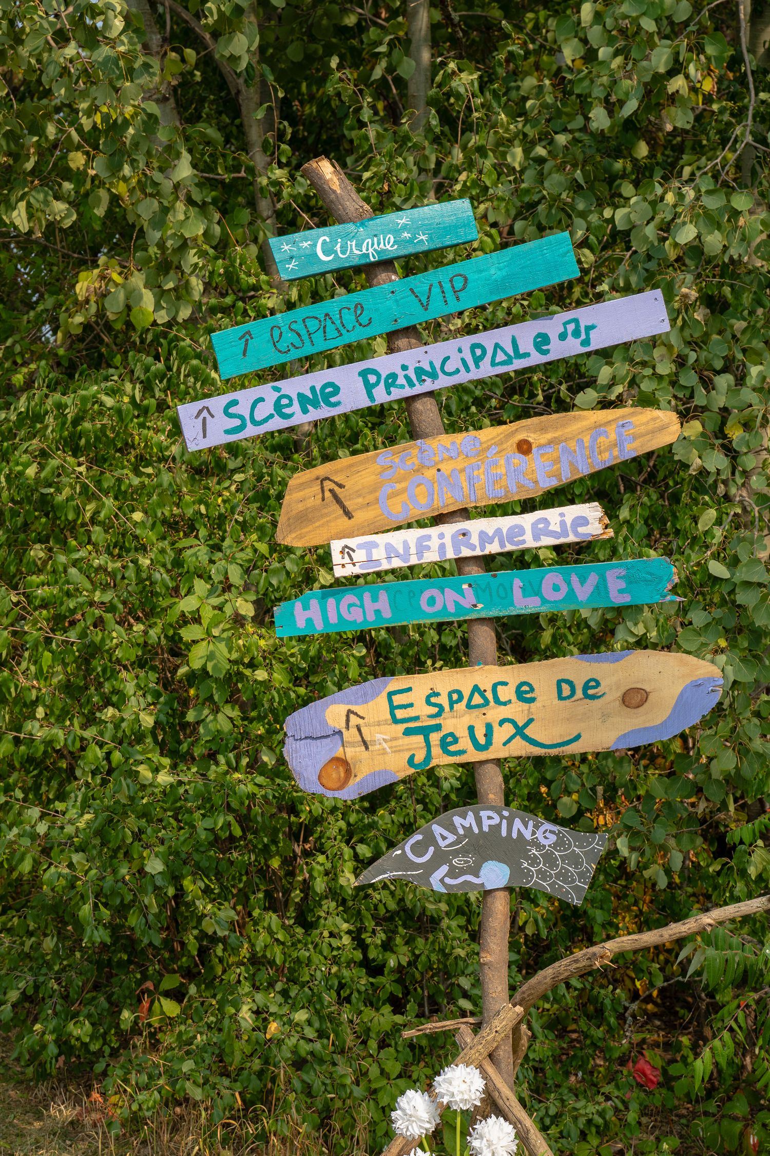 Panneaux en bois faits main, décorés de motifs colorés, indiquent les différentes zones de l’Anatha Fest à Montréal.