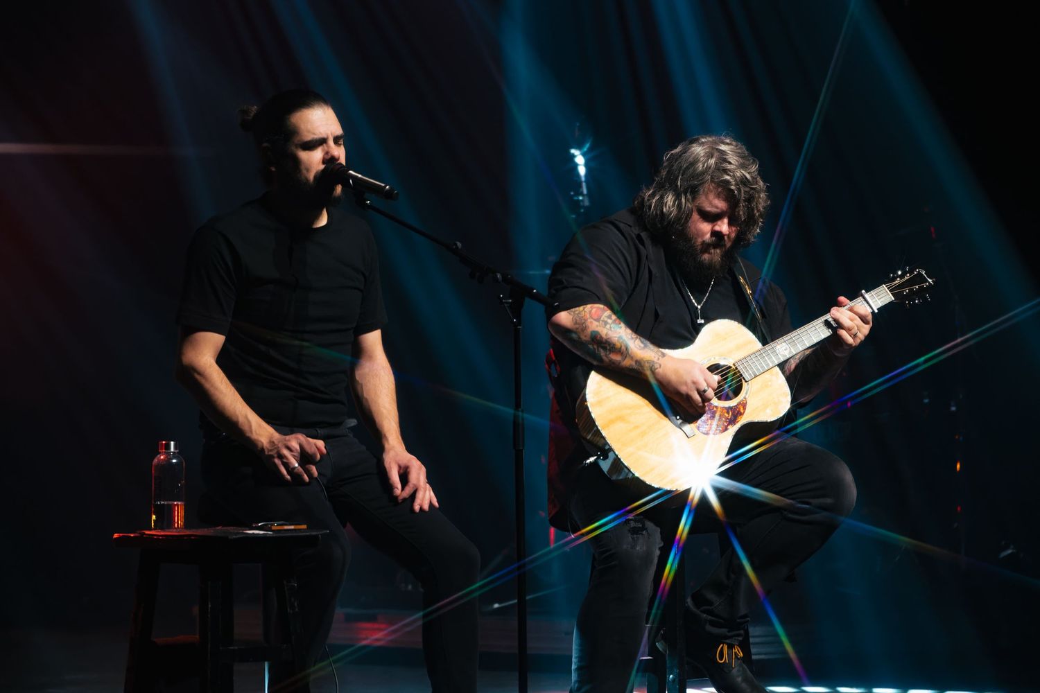 Concert des 2Frères, Sonny joue de la guitare avec des reflets de lumière et Érik chante au micro a La Baie Saguenay.