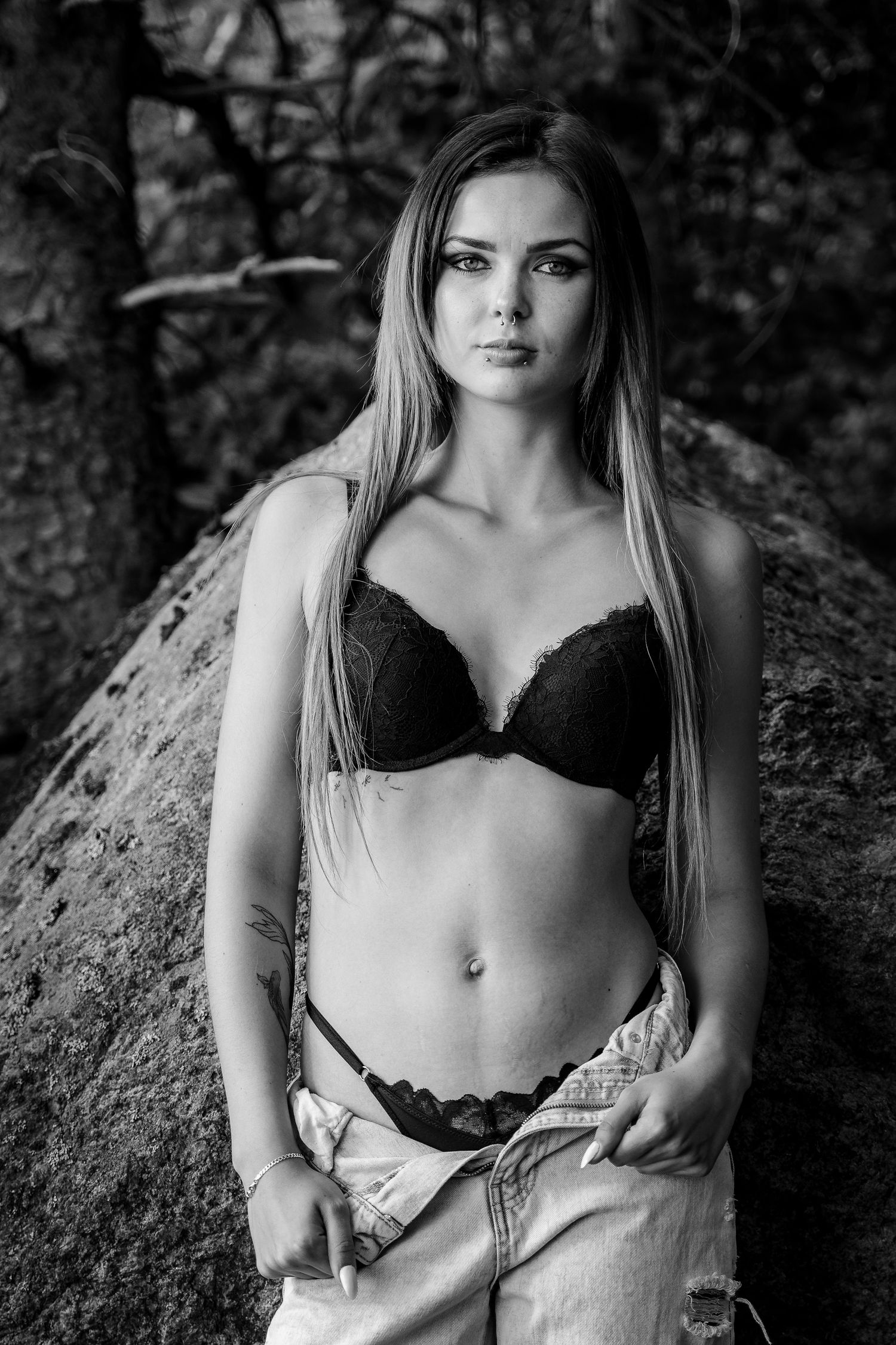 Portrait boudoir en noir et blanc d’une modèle debout devant un rocher
