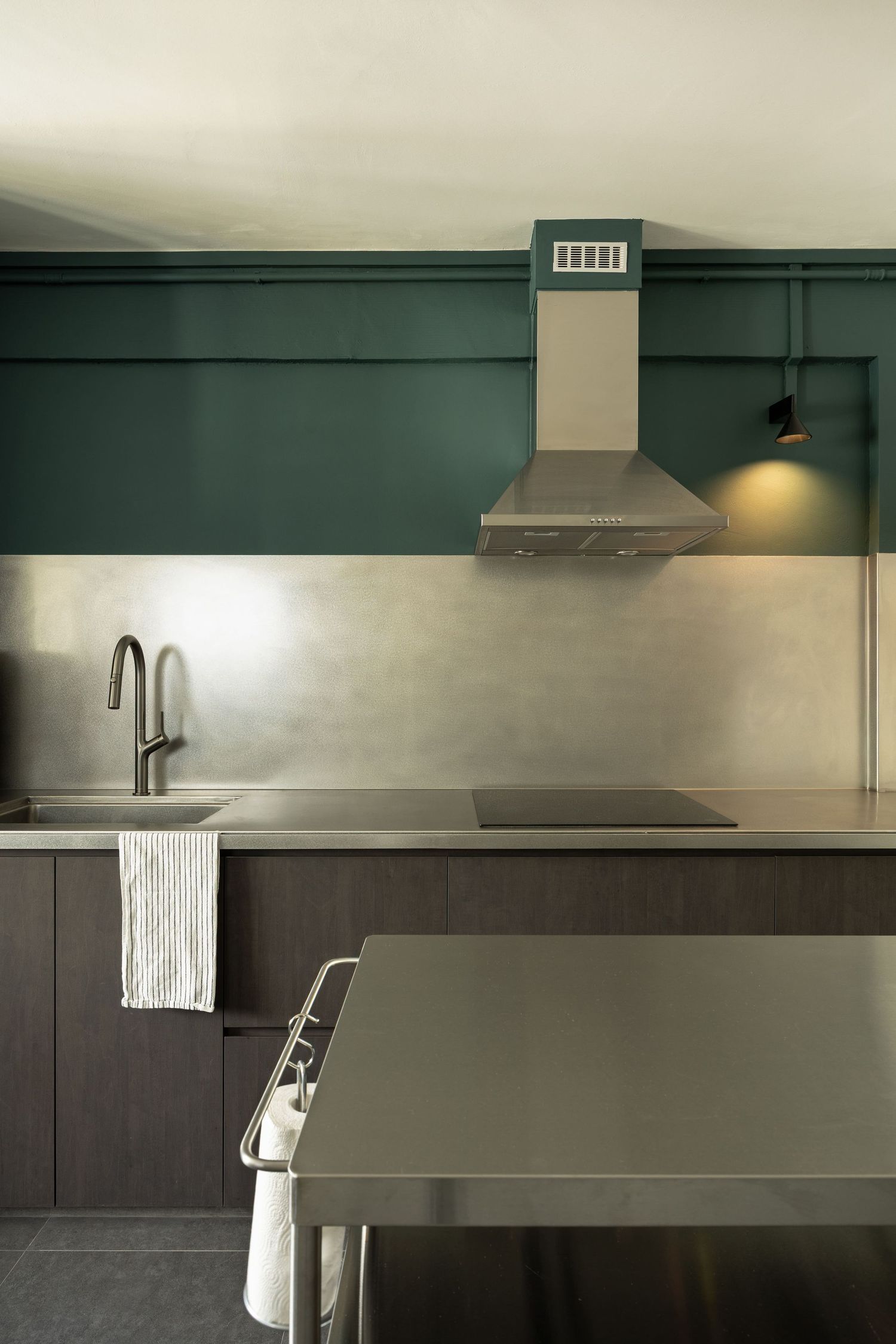 Modern kitchen design featuring sleek dark cabinets and stainless steel appliances with minimalist hardware and lighting.