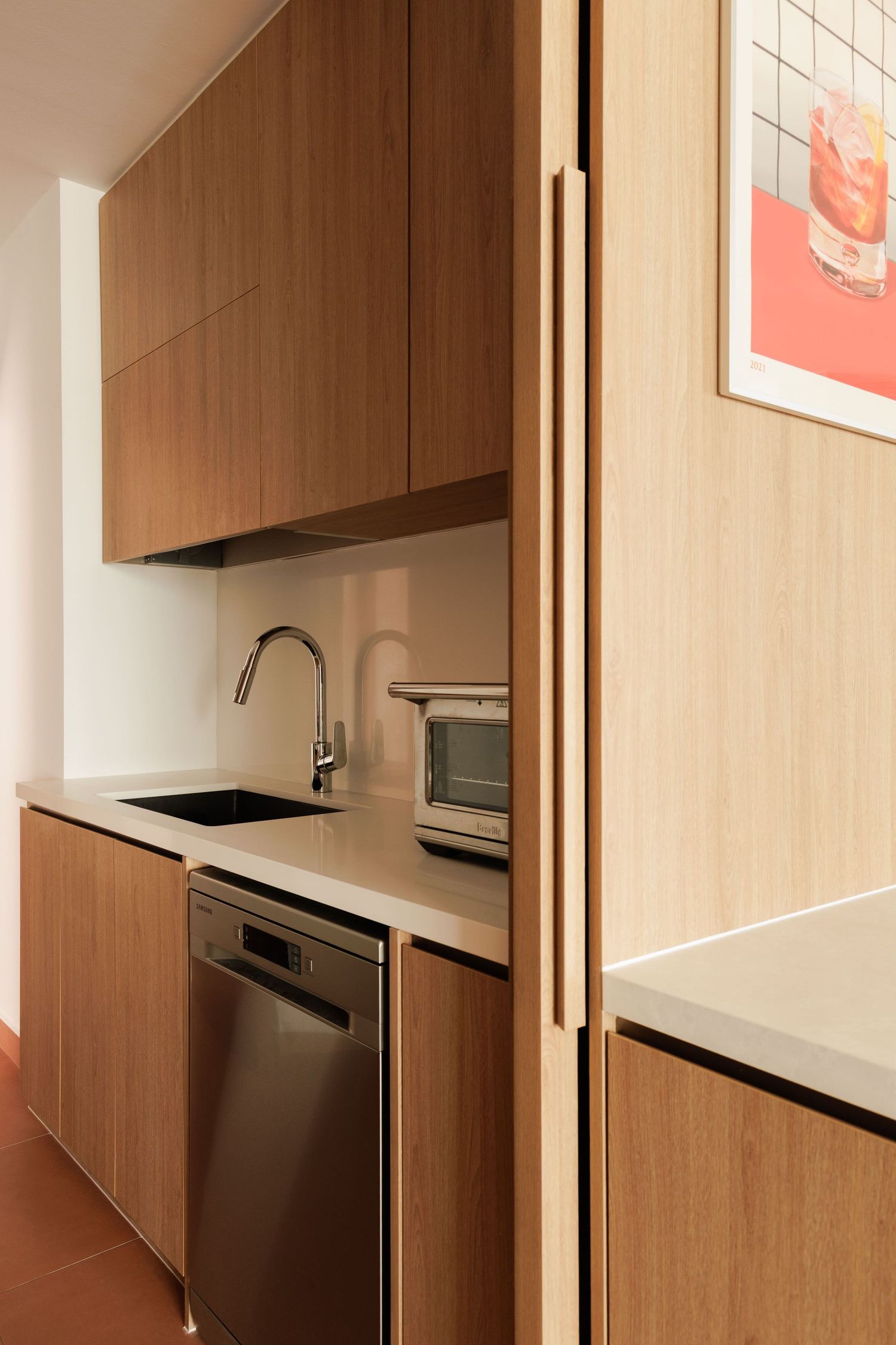 Modern wood-paneled kitchenette with sleek built-in appliances and minimalist cabinetry in warm brown tones.