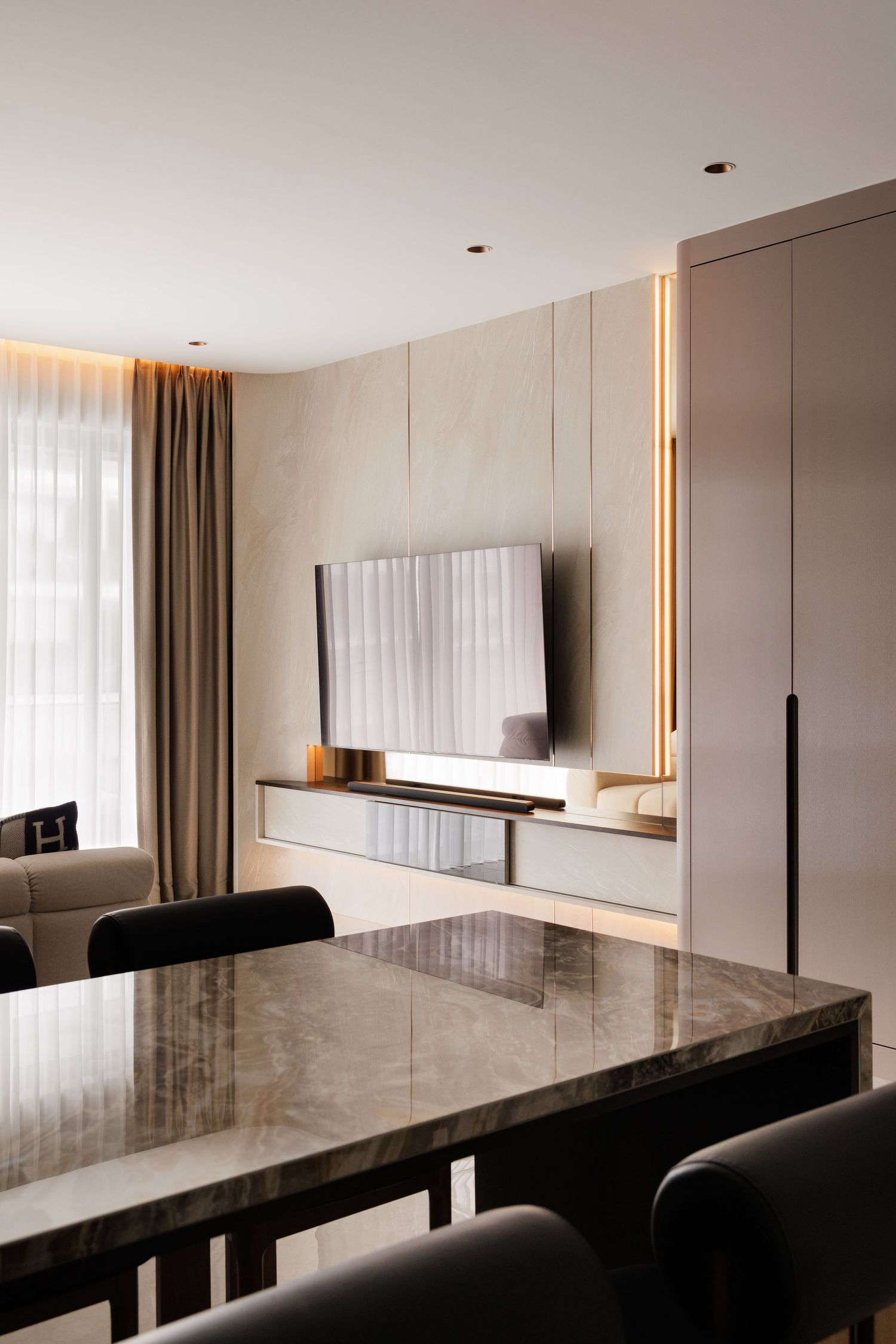 Modern minimalist interior with sleek marble countertop and neutral tones featuring white walls and sheer curtains.