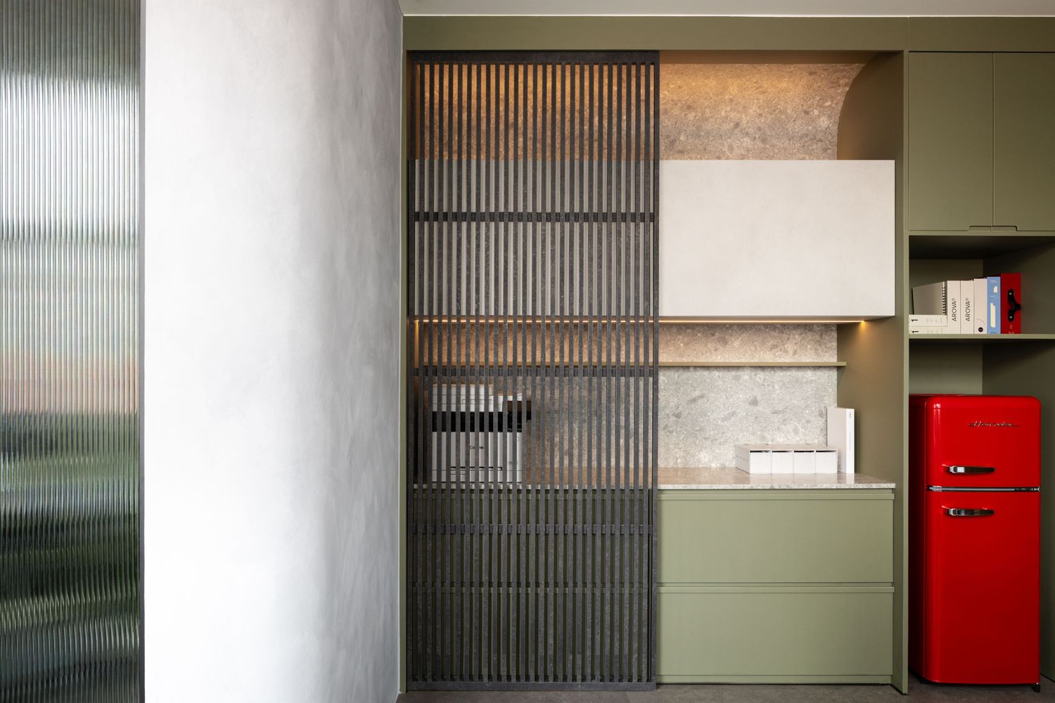 Modern interior design featuring a red refrigerator, olive green cabinets, and ribbed glass partition wall accents.