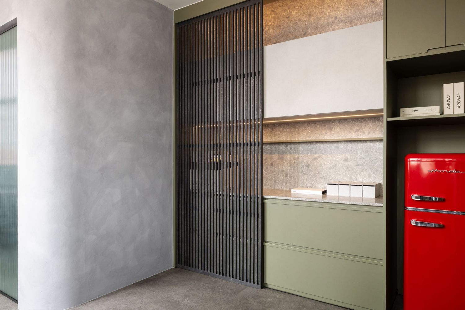 Modern interior design featuring olive green cabinets, concrete wall texture, and a retro red mini fridge.