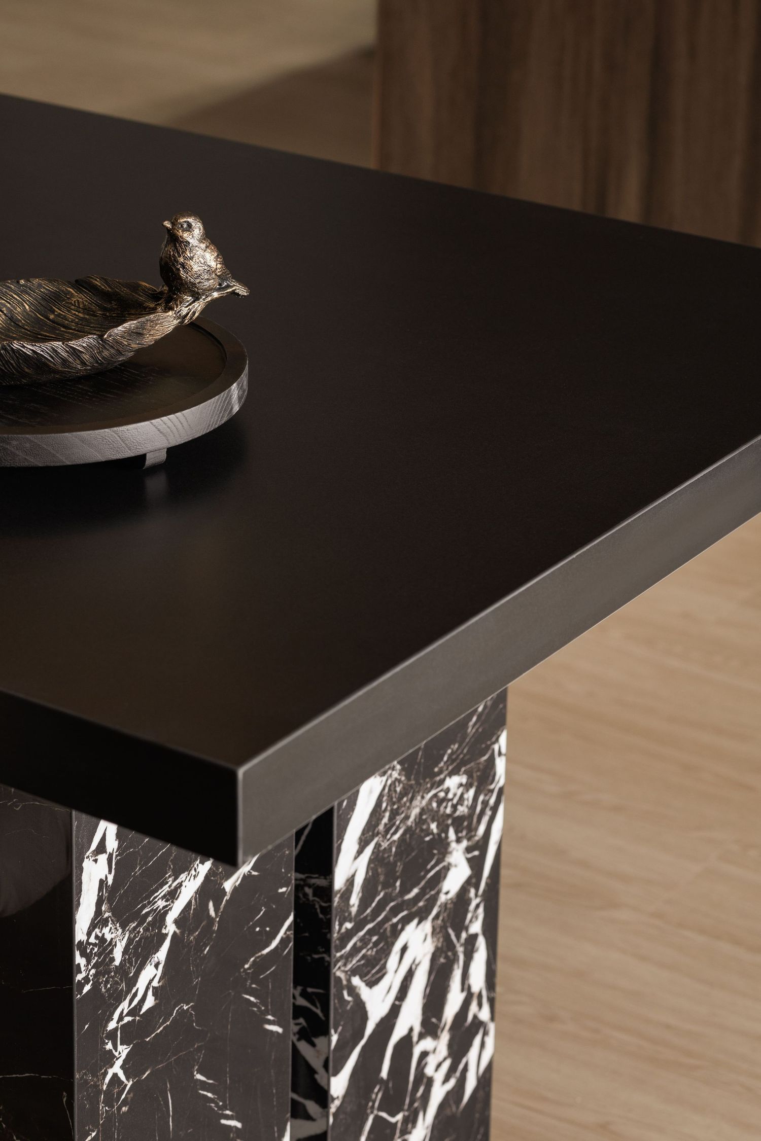 Black marble-legged console table with dark top, featuring a decorative bronze bird figurine on a round tray.