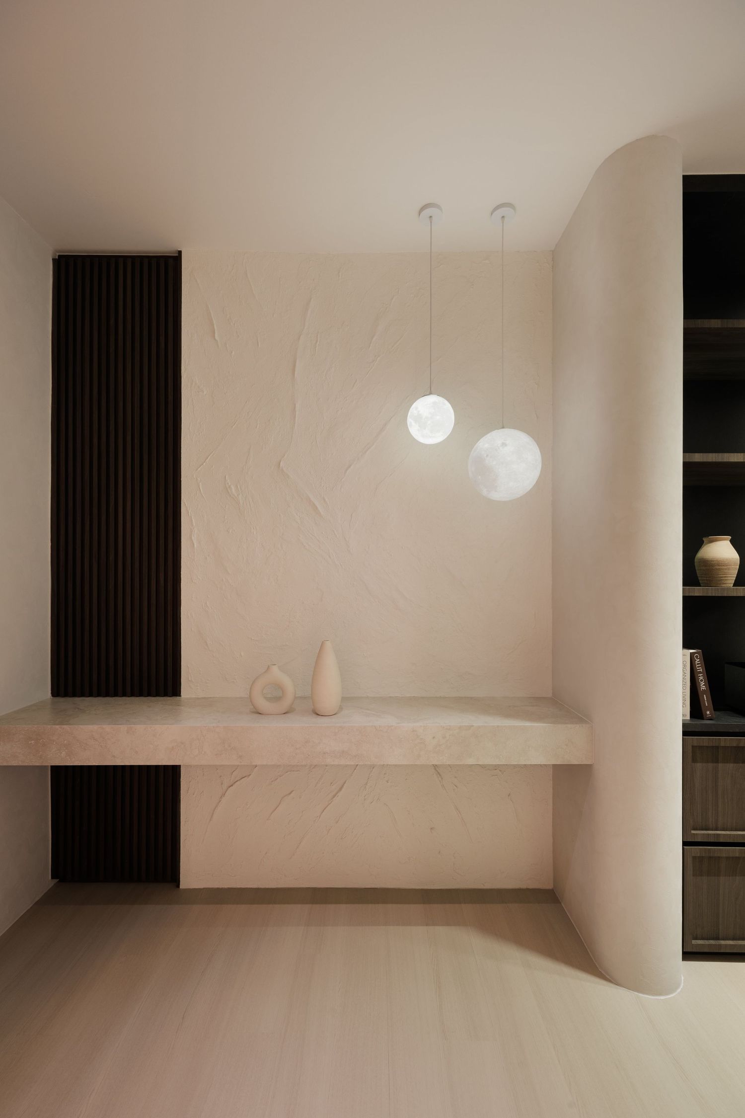 Minimalist interior space with curved white walls, pendant lights, and black vertical radiators creating a serene atmosphere.