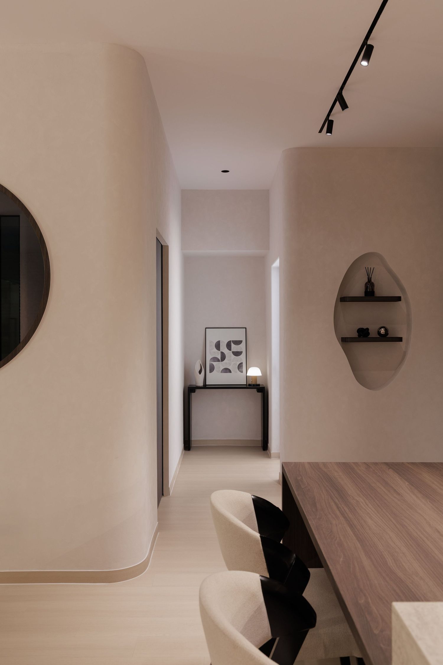 Modern minimalist interior hallway with curved white walls, floating shelves, and light wood flooring.