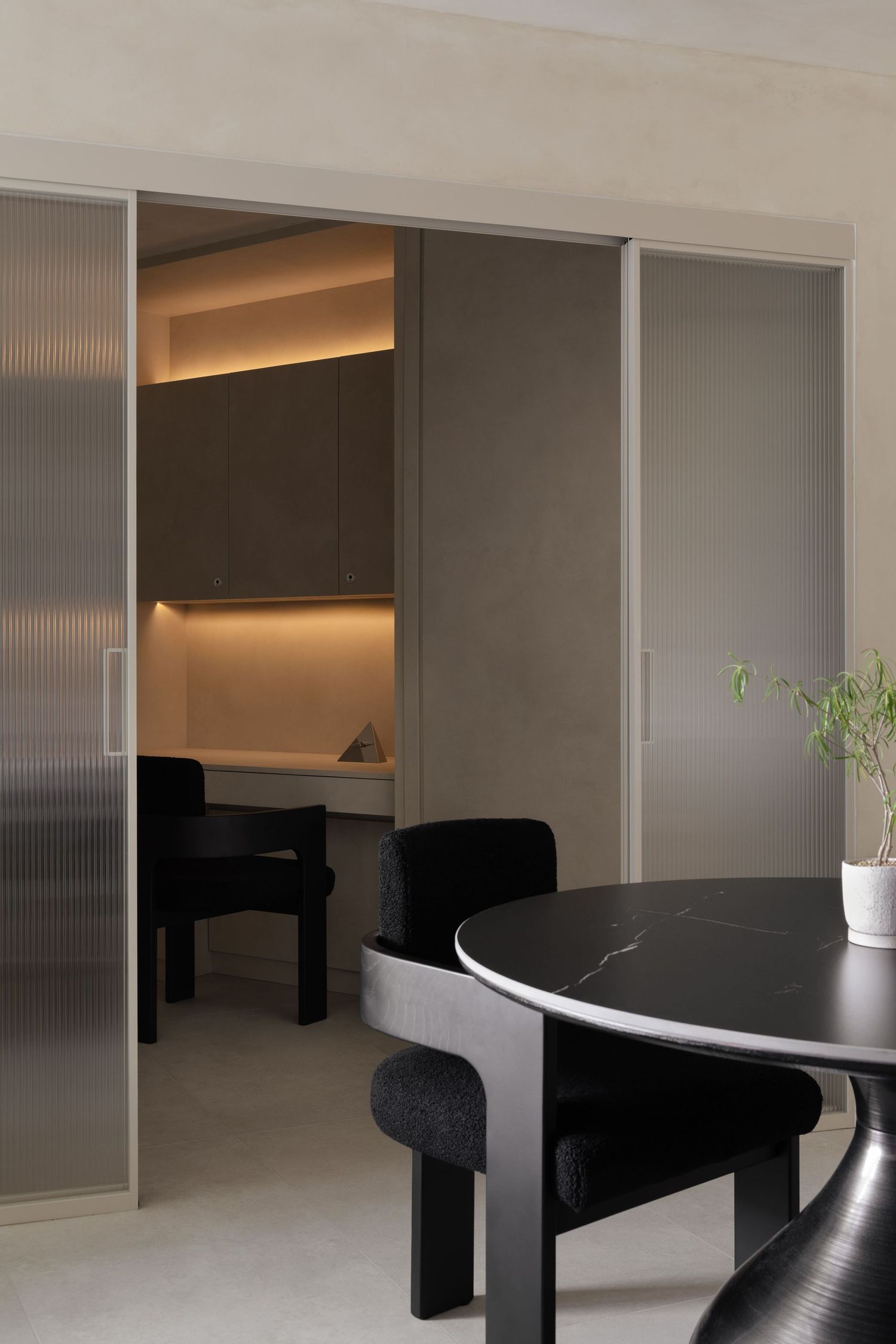 Modern minimalist interior space with black furniture and frosted glass partitions creates a sleek office environment.