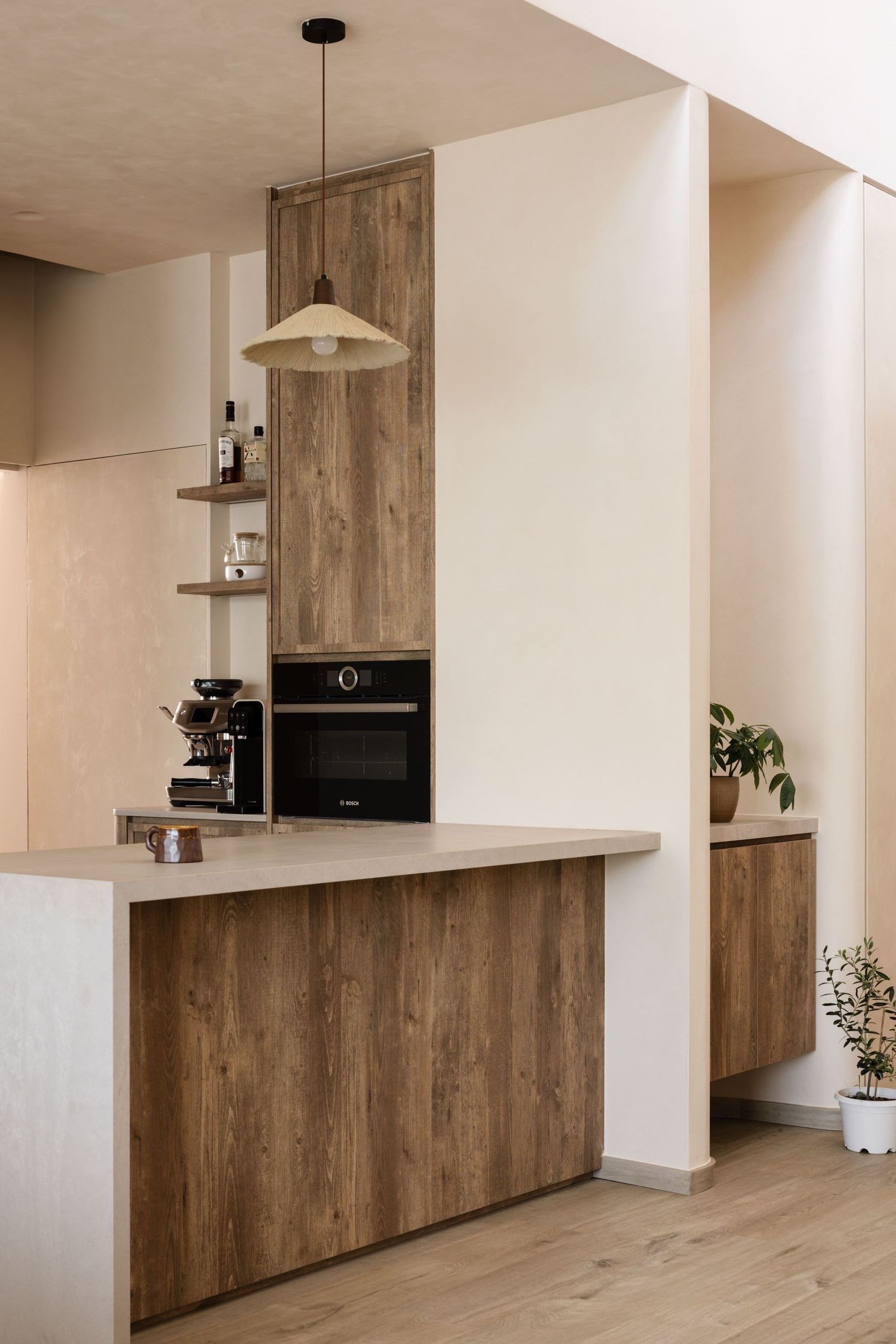 Modern minimalist kitchen featuring warm wood cabinets, white walls, pendant lighting and built-in appliances with open shelving.
