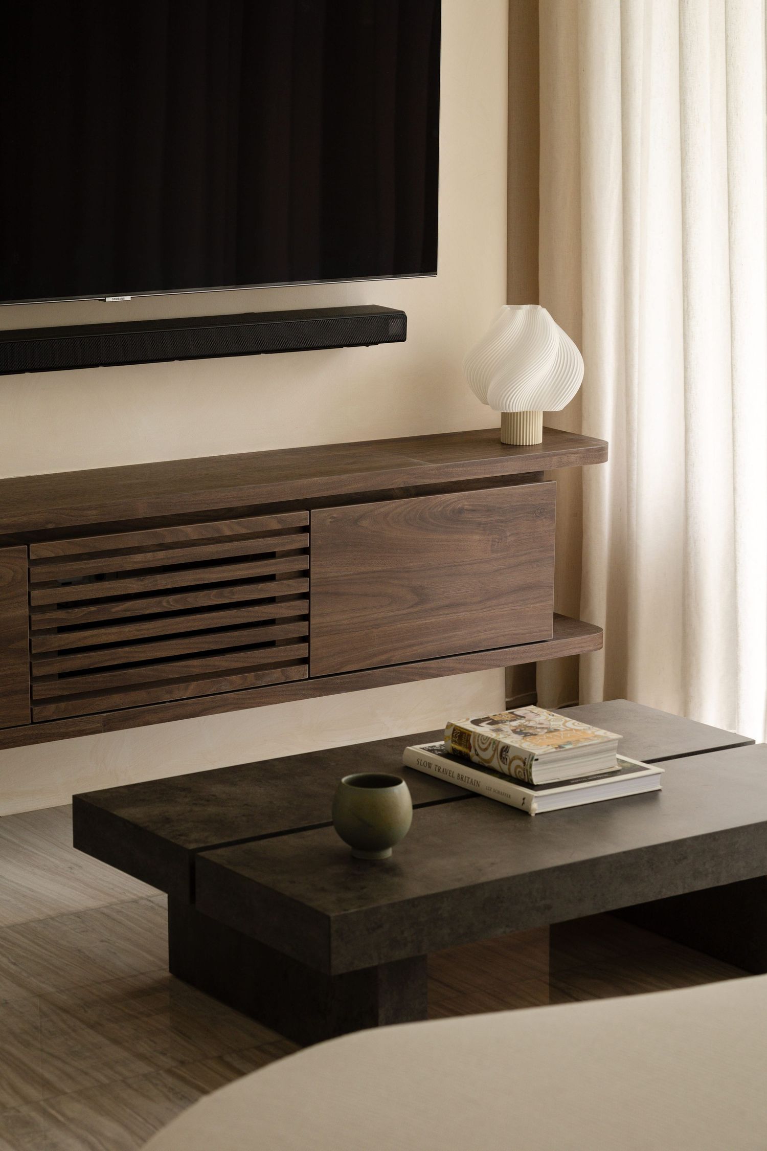 A sleek modern floating entertainment center wall unit in dark wood with slatted panels and minimalist design.
