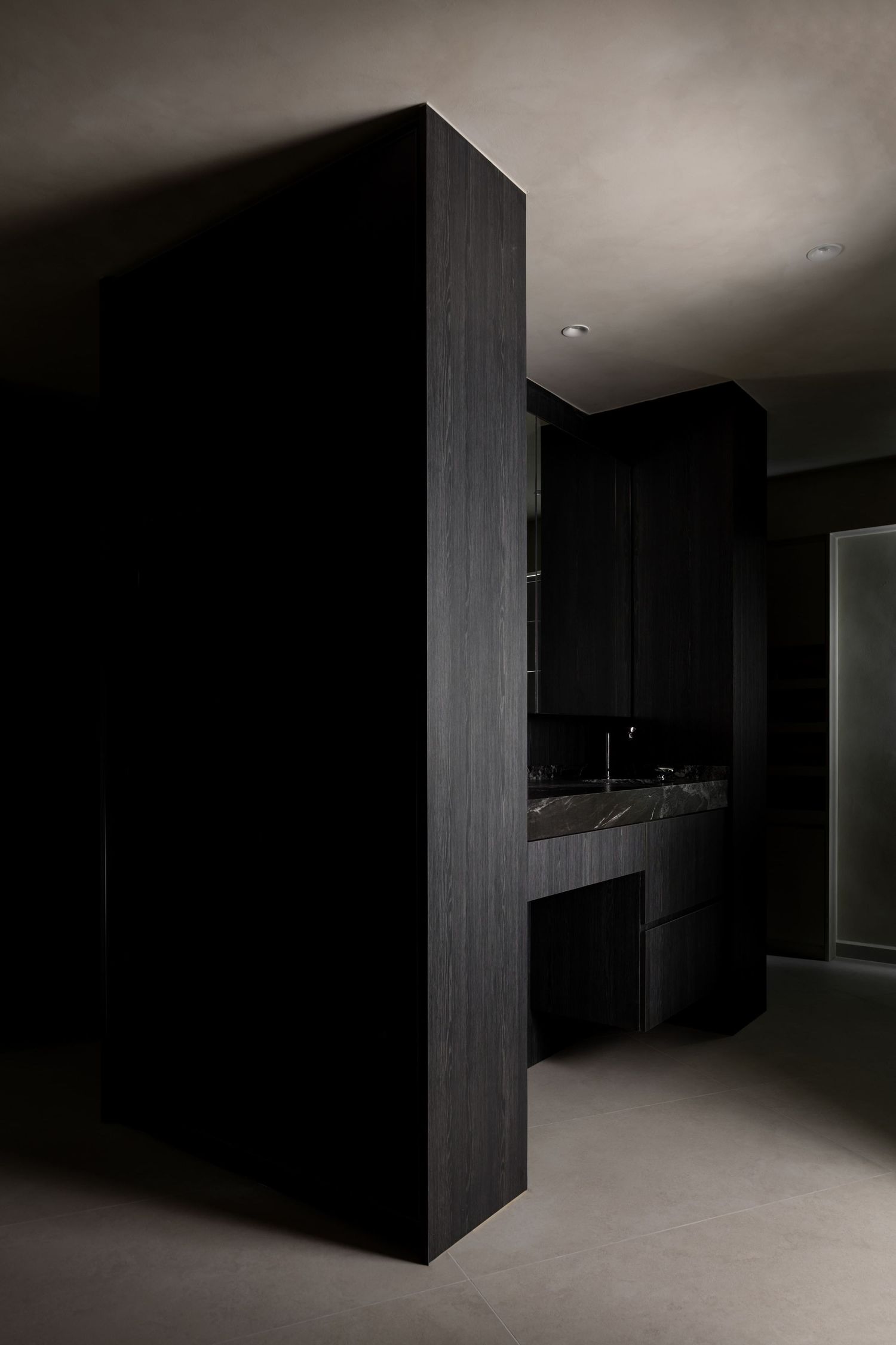 Dark minimalist interior hallway with black walls and dramatic lighting creates a moody architectural atmosphere.