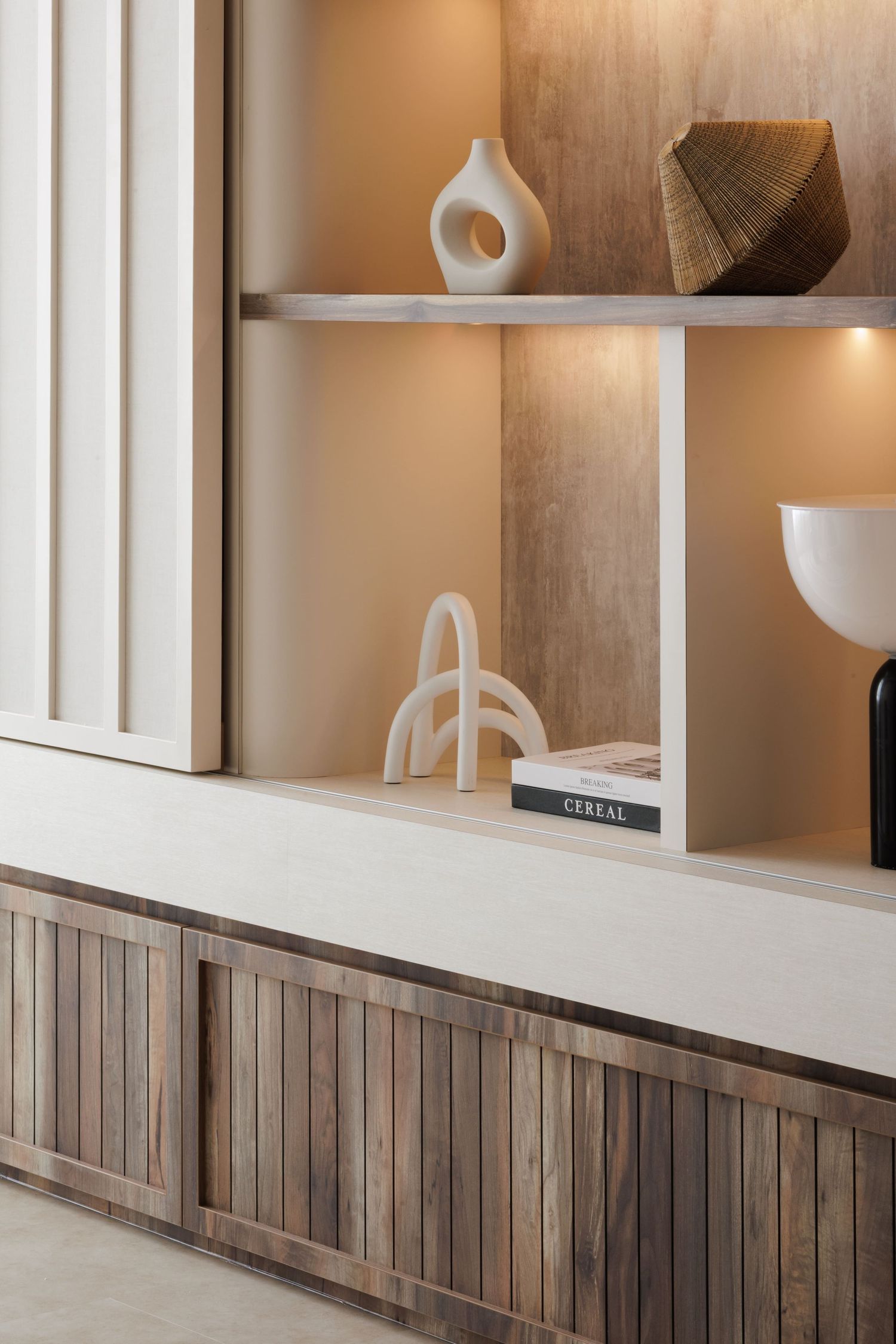 Contemporary interior design with wooden paneling and white display shelves featuring modern decorative objects and sculptures.