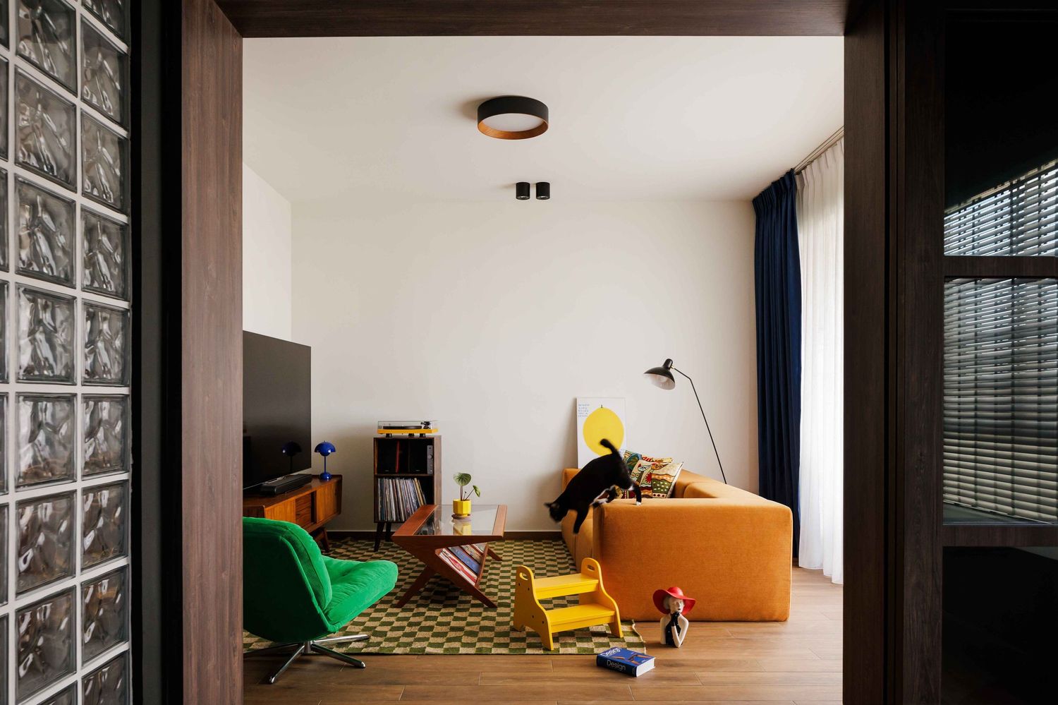 Modern corner living room with black accent wall and bright yellow lounge chair features minimalist interior design.