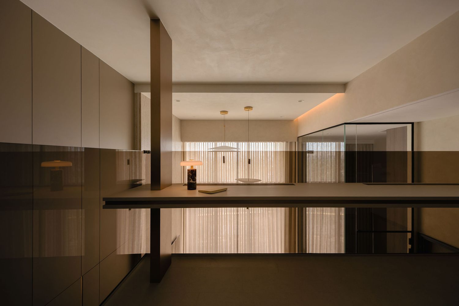 Modern minimalist interior with warm ambient lighting, glossy bronze-toned panels, sheer curtains, and a sleek floating counter.