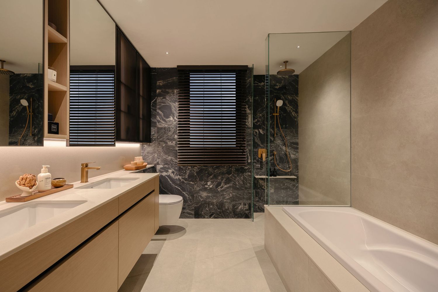 Modern luxury bathroom with dark marble feature wall, floating wood vanity, glass-enclosed shower, freestanding tub and warm LED lighting.