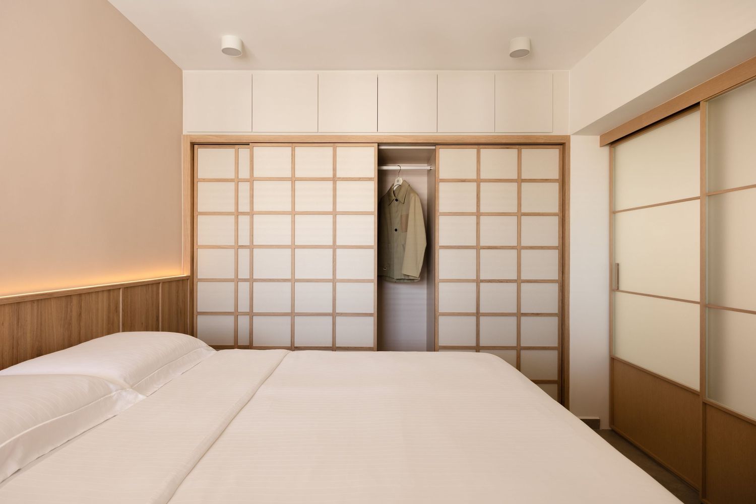 Modern Japanese-style bedroom interior with white walls, sliding shoji screens, and minimalist wooden furniture.