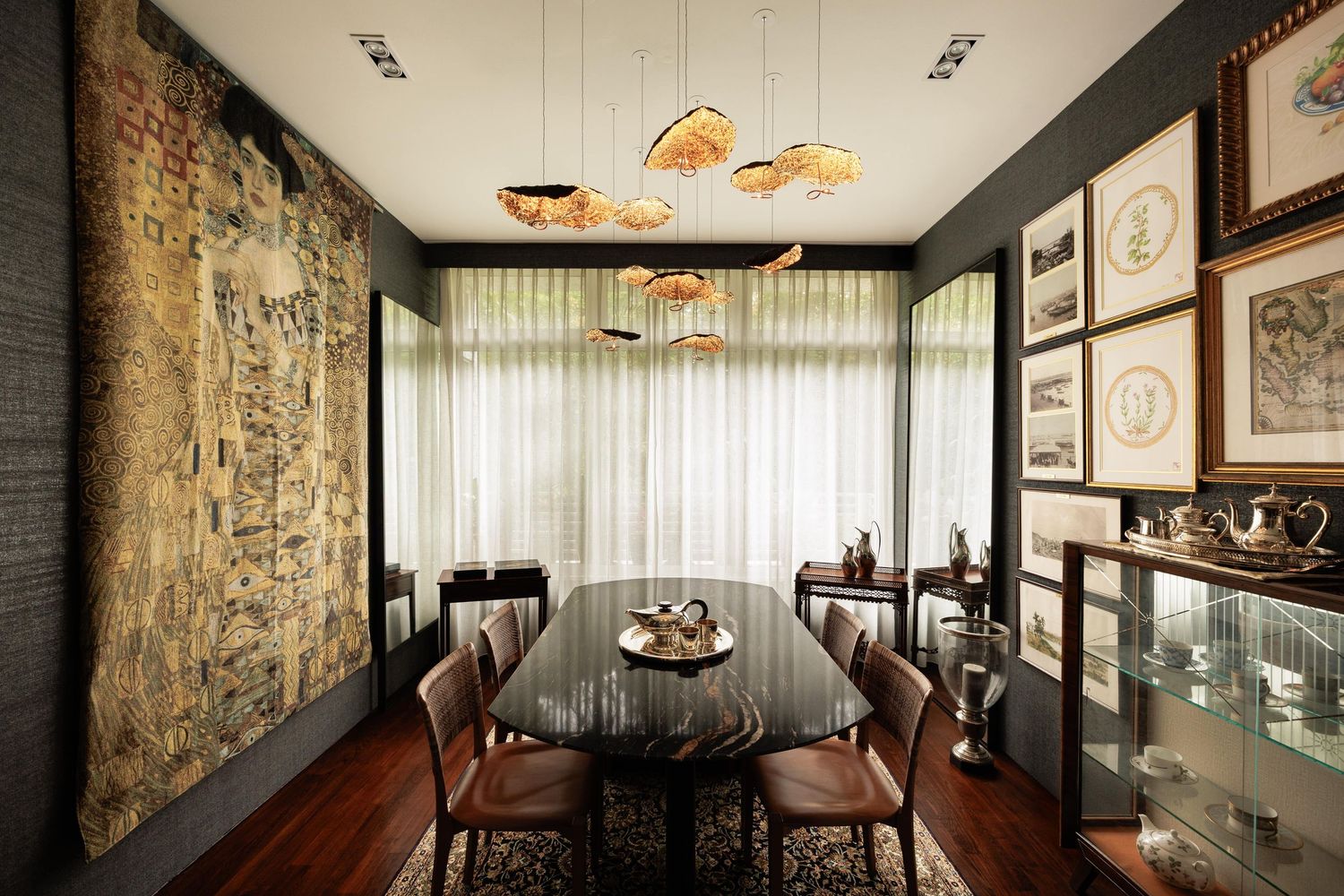 Modern restaurant interior with hanging pendant lights, leather banquette seating, and framed artwork along stone walls.