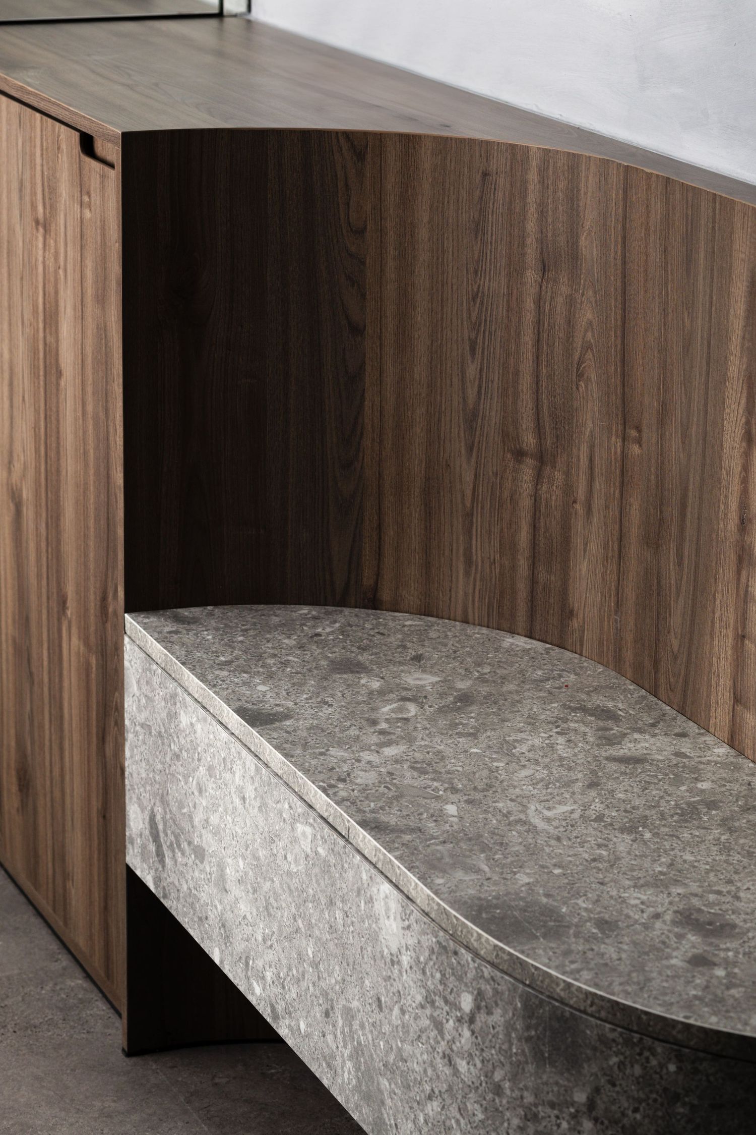 Modern curved storage unit features wood paneling and a sleek gray marble-textured surface.