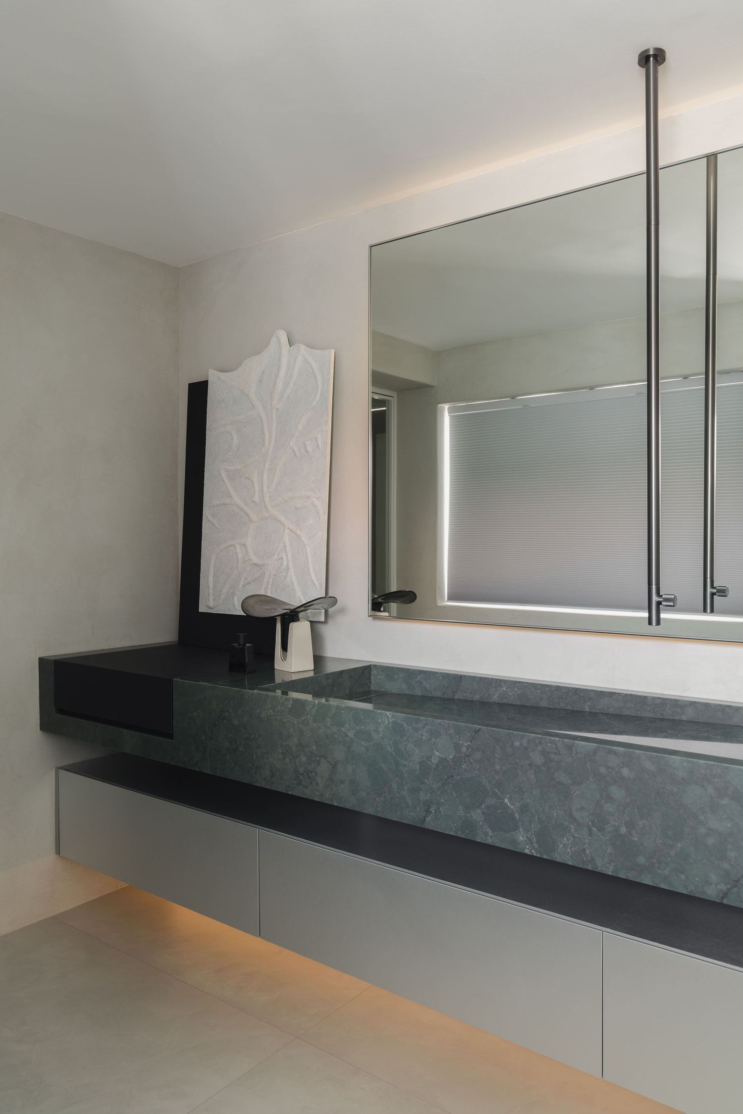 Modern bathroom with dark green marble floating vanity, large mirror, and warm under-cabinet lighting.
