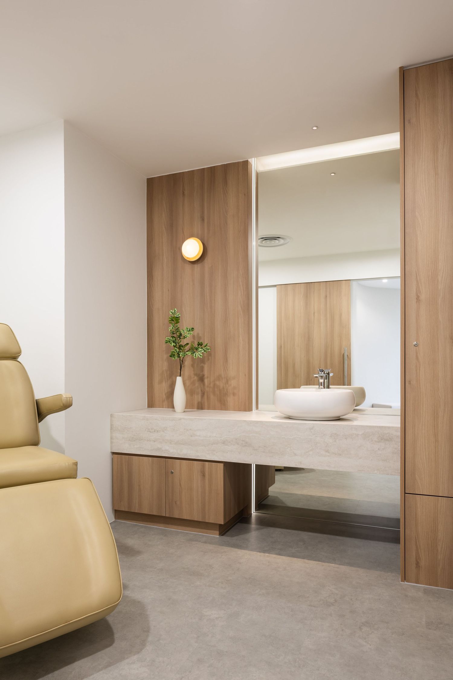 Minimalist spa interior with natural wood panels, concrete floors, beige furniture and clean white walls creating a serene atmosphere.