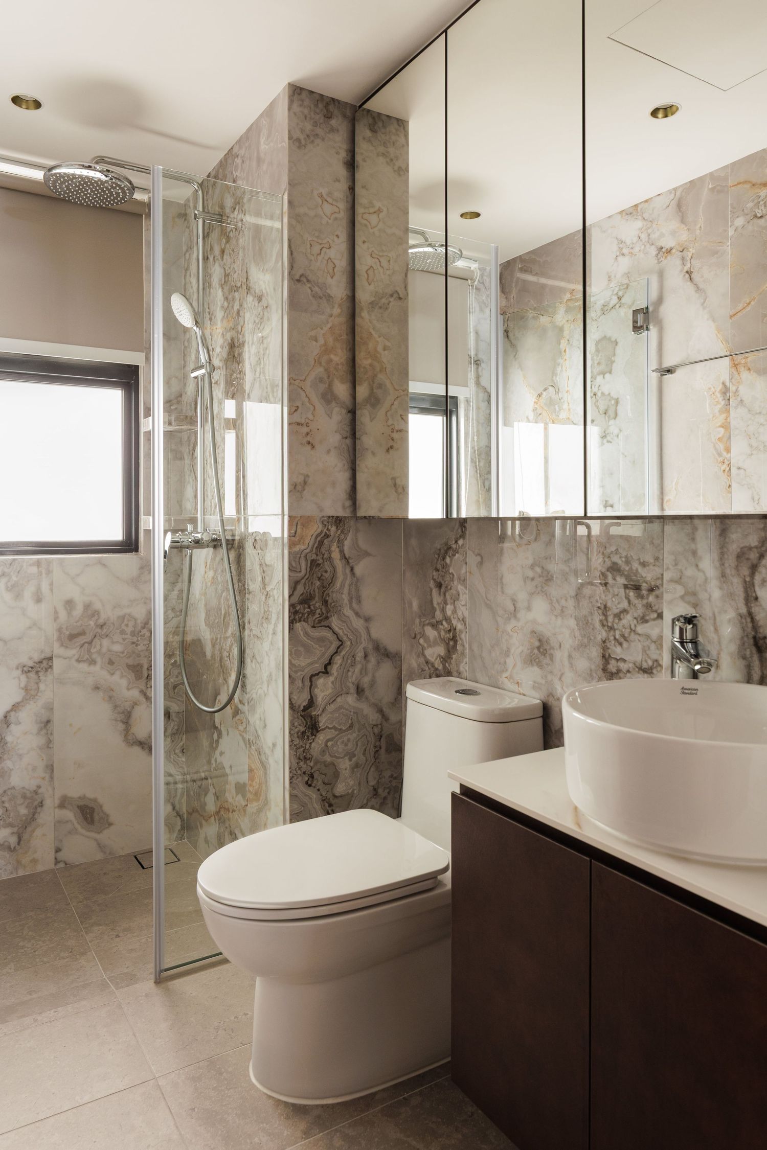 Modern bathroom with marble walls, floating vanity, oval freestanding tub, and glass shower enclosure.