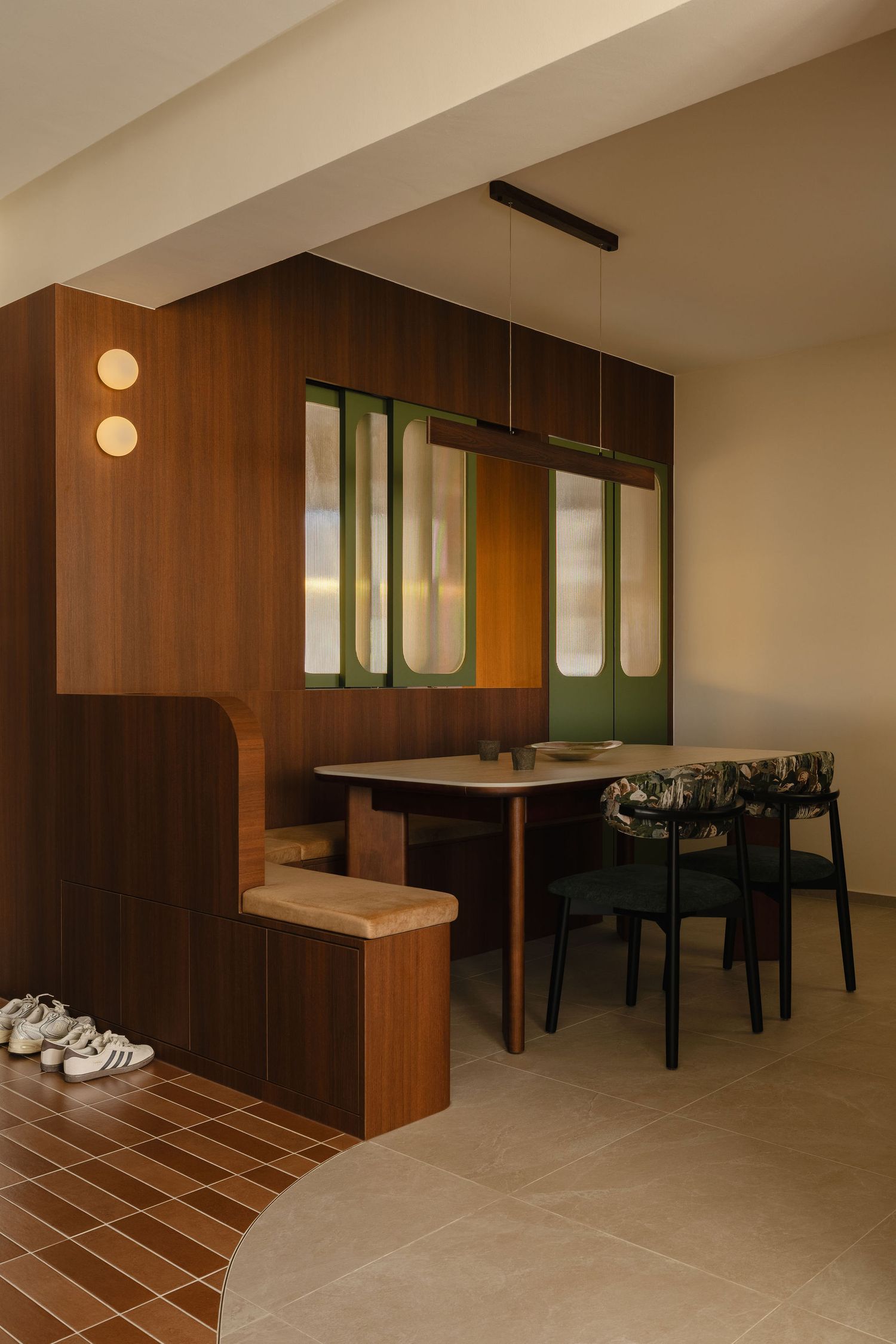 Modern dining nook with built-in wood bench seating, green framed glass doors, a round table, black chairs and terracotta herringbone tile e