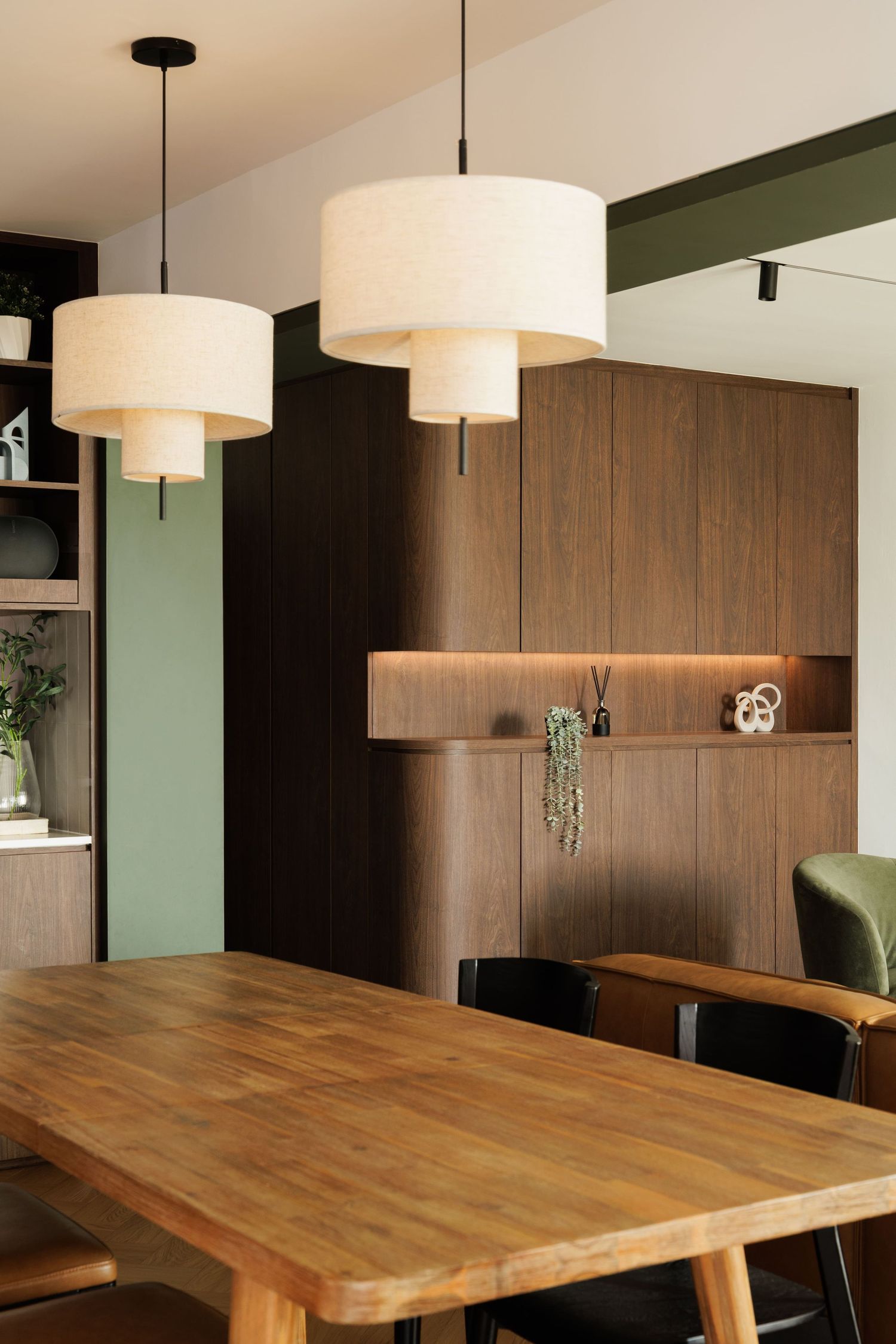 Modern dining room with wooden table and pendant lights showcasing sleek wood paneling and minimalist design elements.