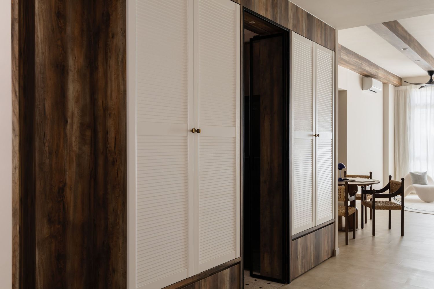 Long empty modern hallway with dark wood panel accents and white walls illuminated by natural light from windows.