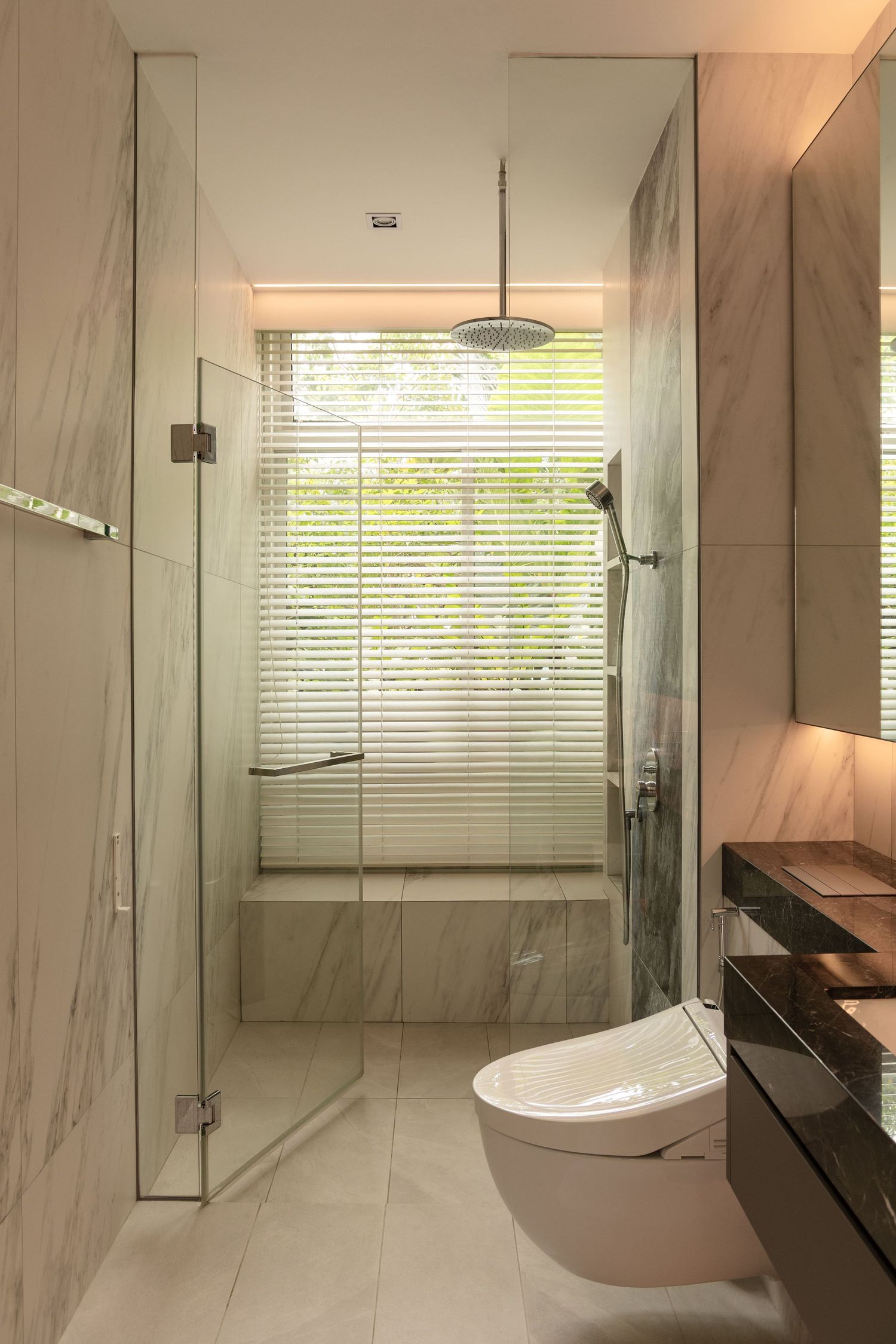 Sleek modern bathroom interior with white marble walls, floating vanity, and natural light from window.