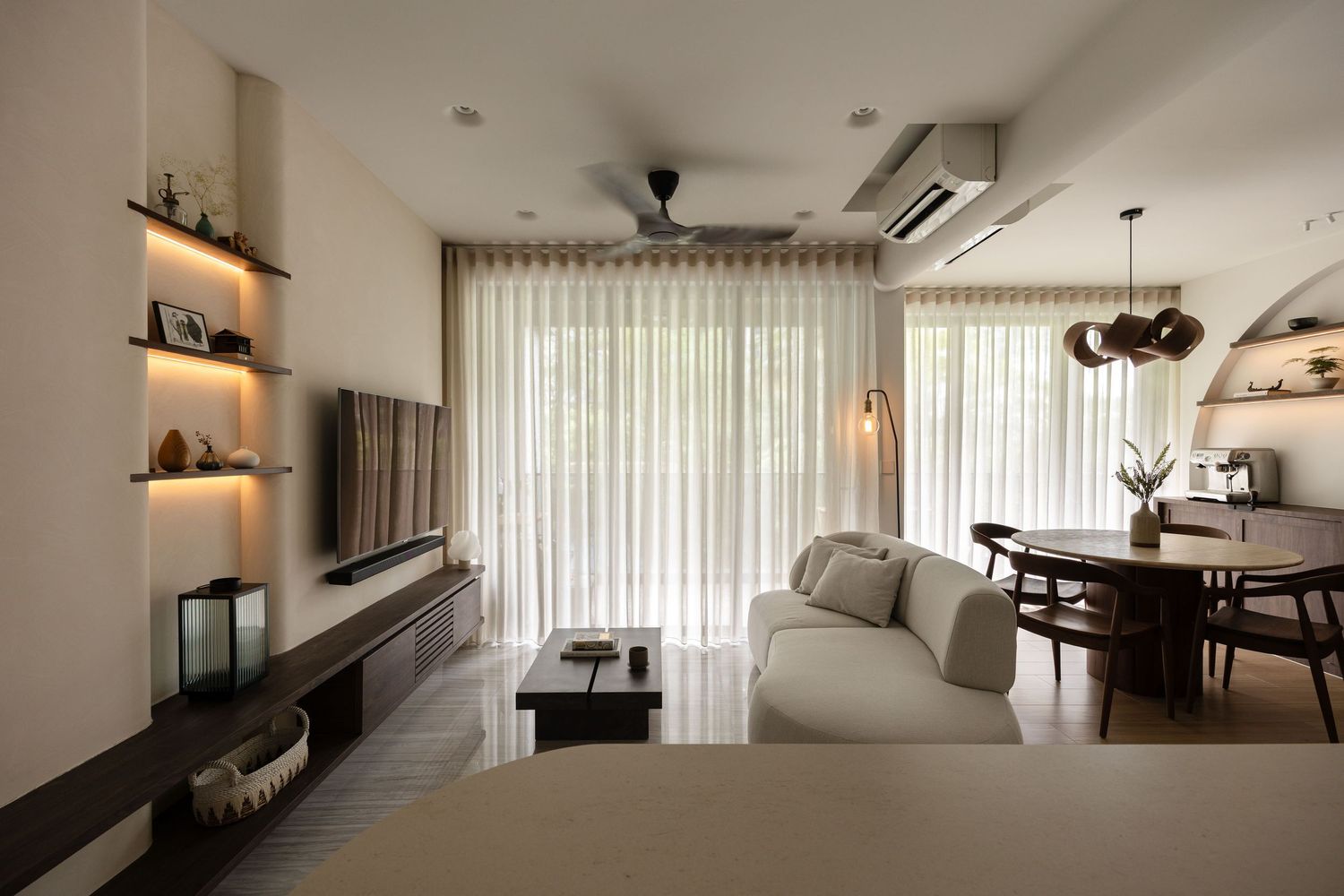 Modern minimalist apartment interior with neutral tones featuring sleek furniture and vertical window treatments.
