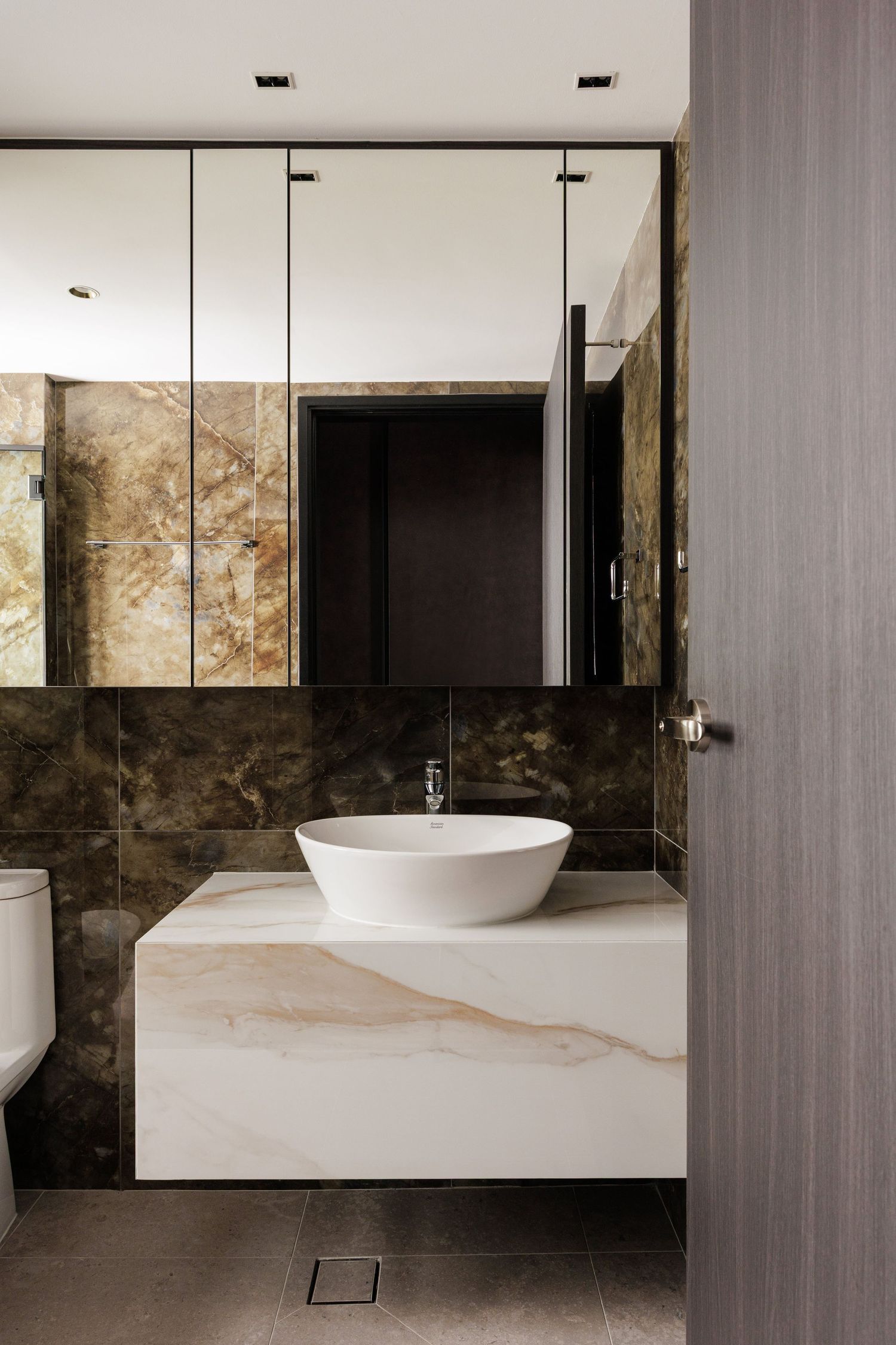 Modern minimalist bathroom with vessel sink, dark stone walls, and white fixtures in a luxurious spa-like setting.