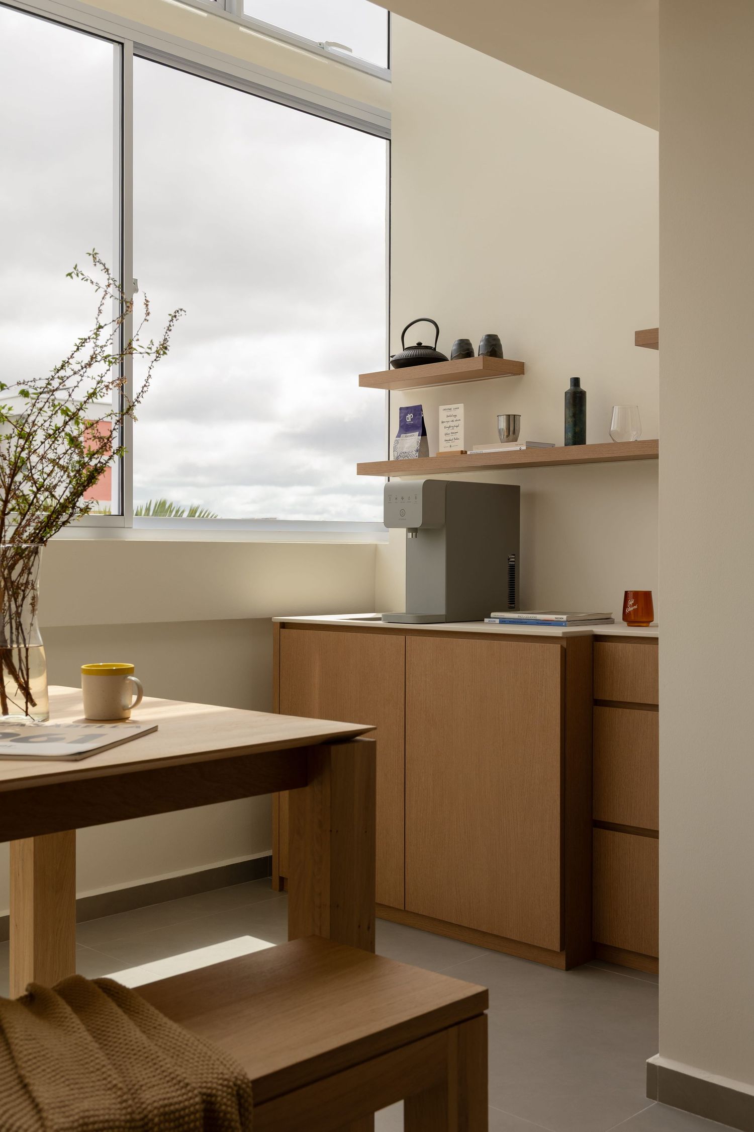 Minimalist interior space with wooden built-in benches and shelving featuring clean lines and natural light from windows.