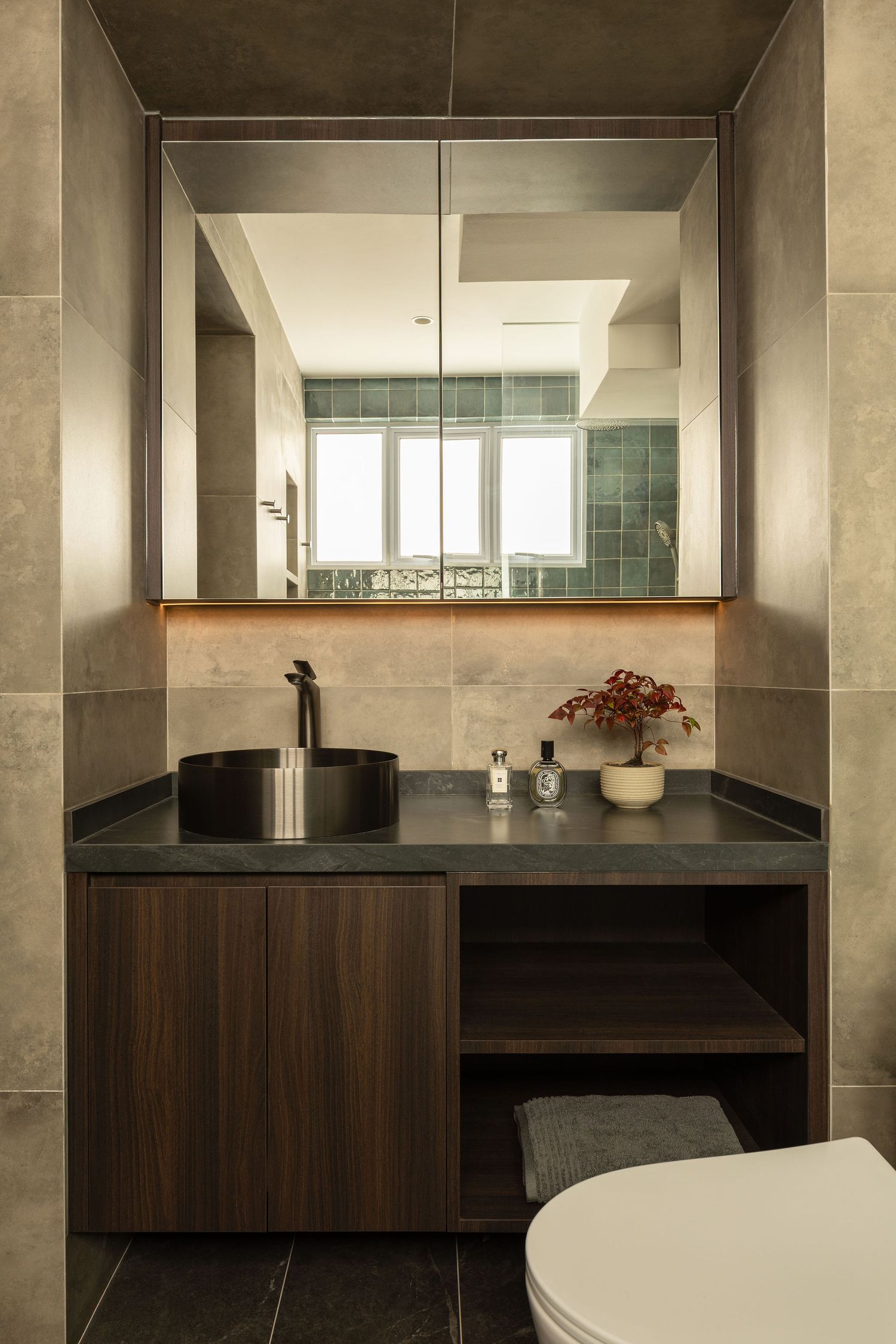 Modern bathroom vanity with dark vessel sink, wooden cabinet, granite countertop, open shelving, and large mirror reflecting natural light.