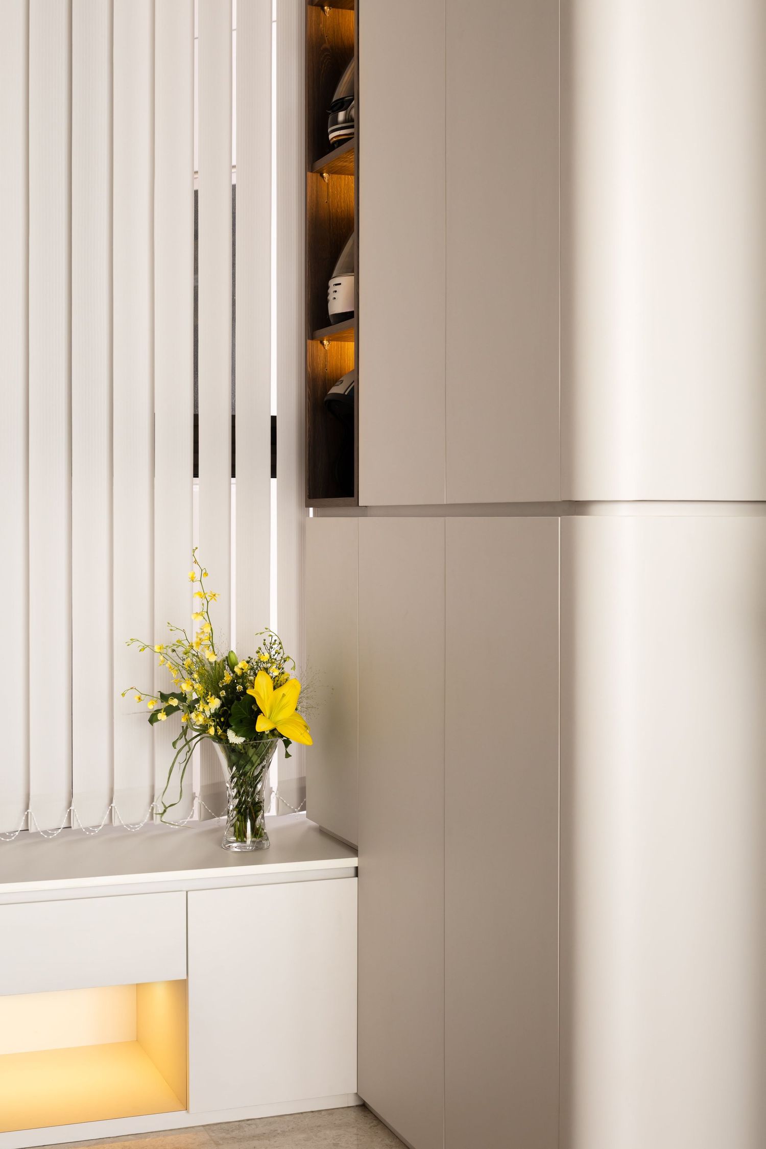 Contemporary white interior with hanging pendant lights and yellow flower arrangements on display shelves.