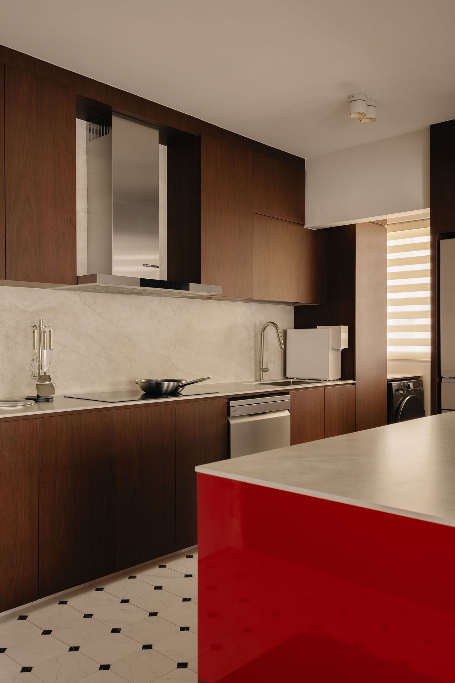 Modern kitchen with dark wood cabinets, marble backsplash, red island, and black-and-white tile flooring.