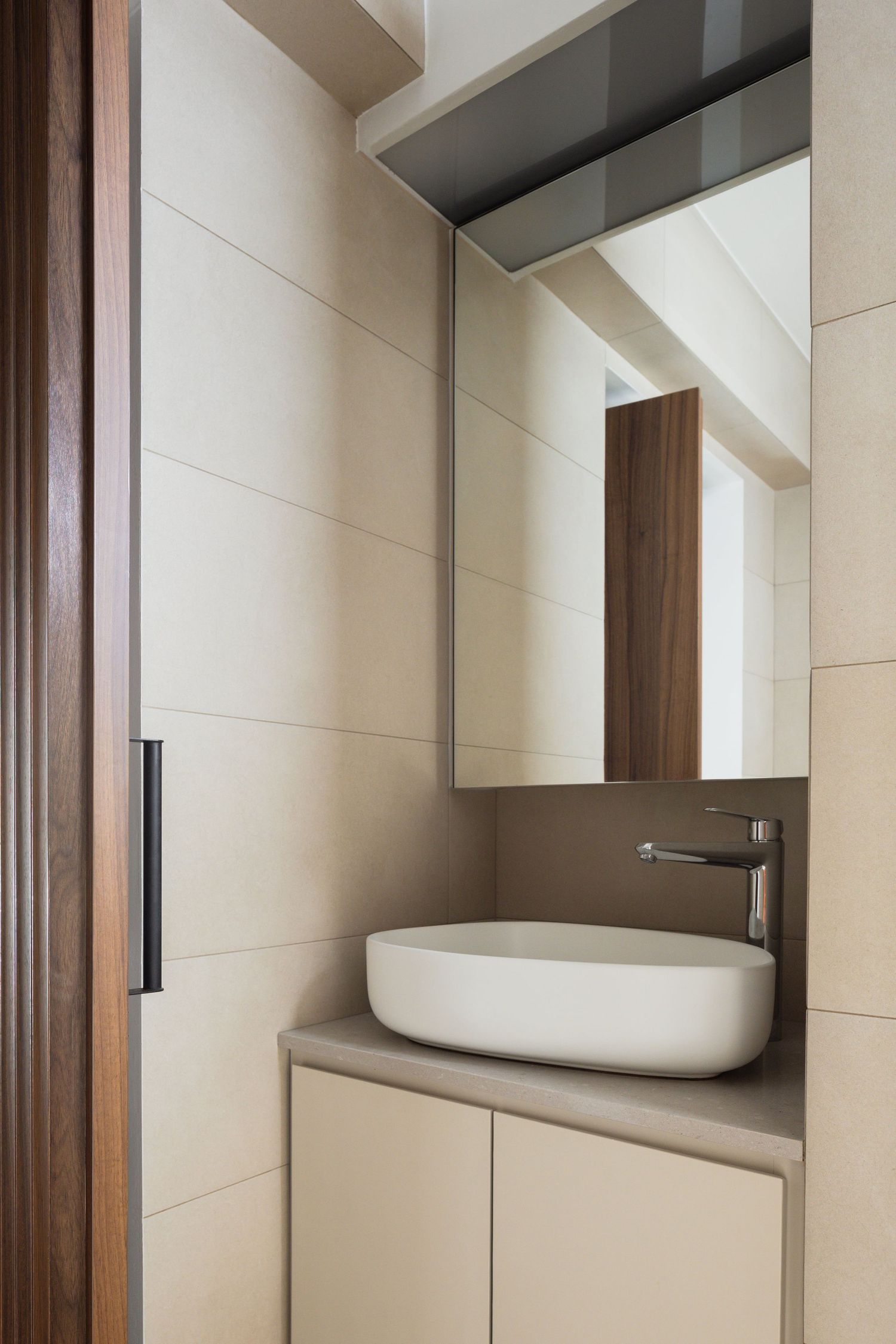 Modern minimalist bathroom with oval vessel sink, cream walls, and wooden accents showcasing clean contemporary design.