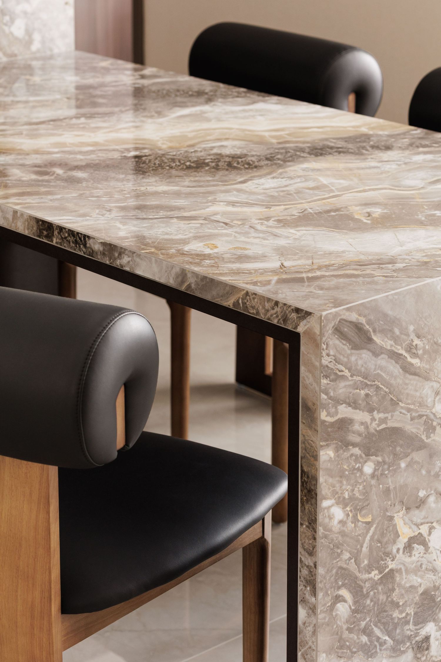 Close-up view of a modern dining set featuring a marble-patterned table top and black leather chair details.